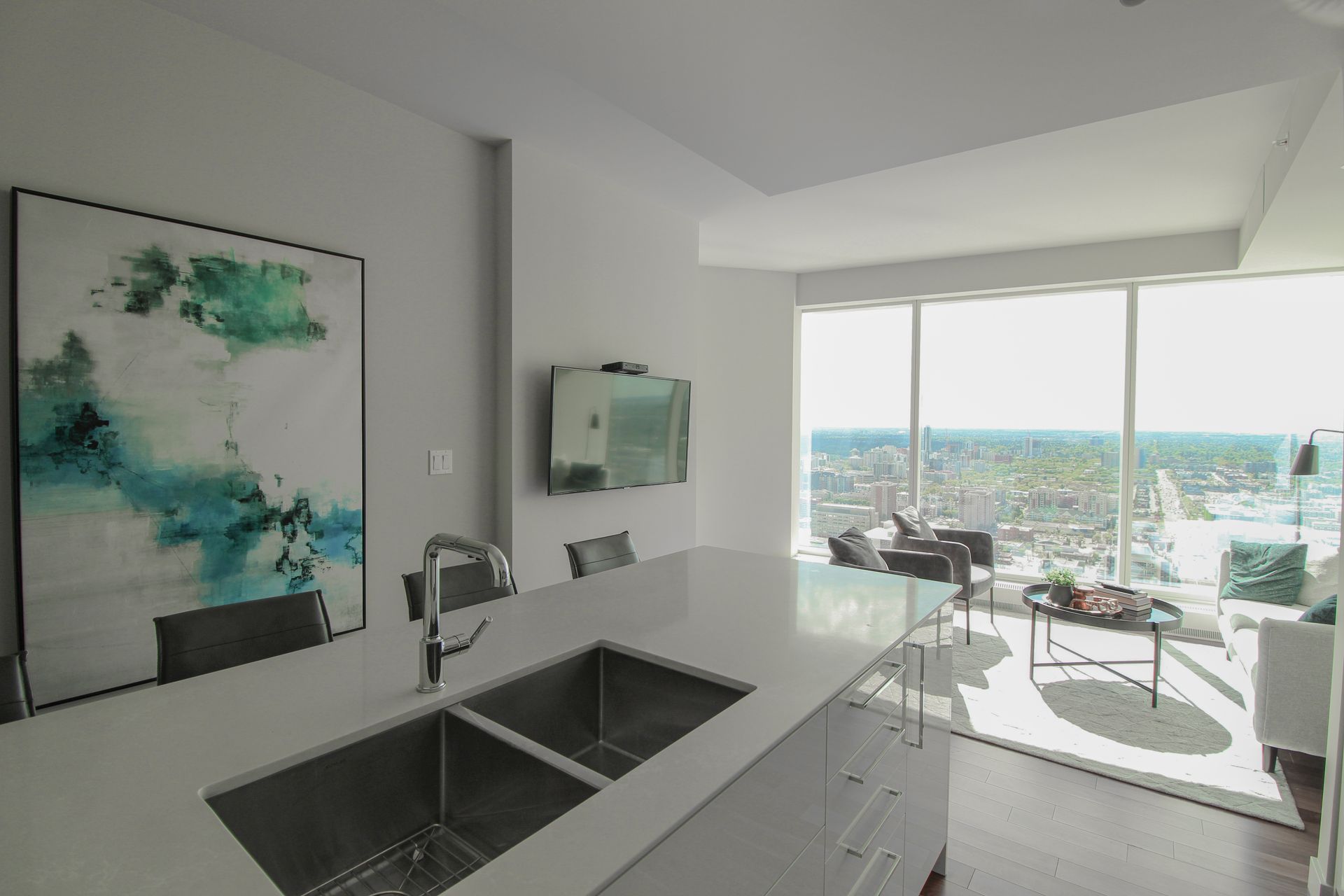 Modern kitchen with a large island and city view through expansive windows.
