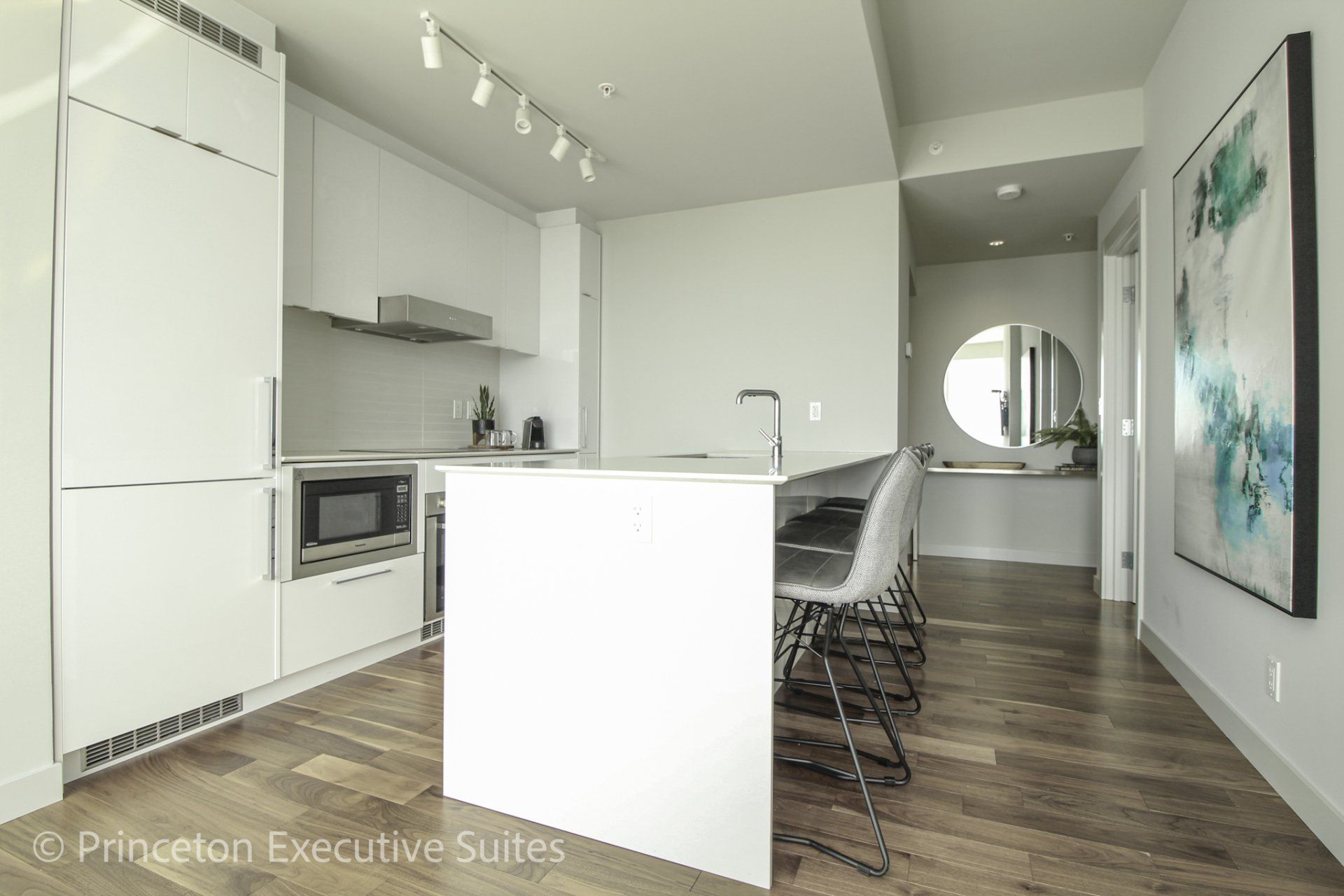 White eating bar with white counter tops and 4 barstools in front of the eating bar inside this edmonton furnished rental