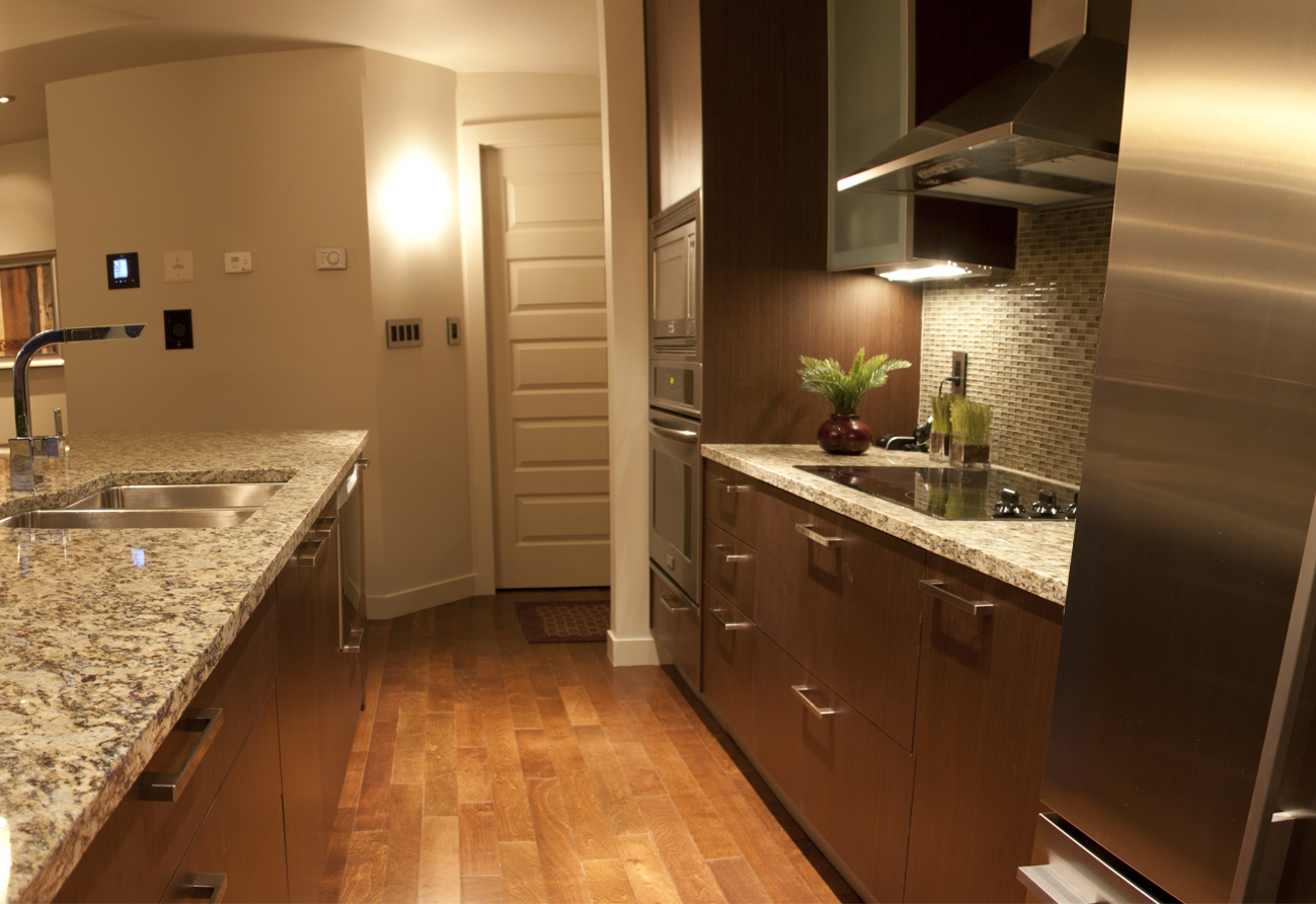 Modern kitchen with granite countertops, dark wood cabinets, stainless steel appliances, and wood flooring.