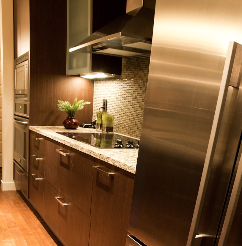 Modern kitchen with stainless steel appliances, dark wood cabinets, granite countertop, and tiled backsplash.