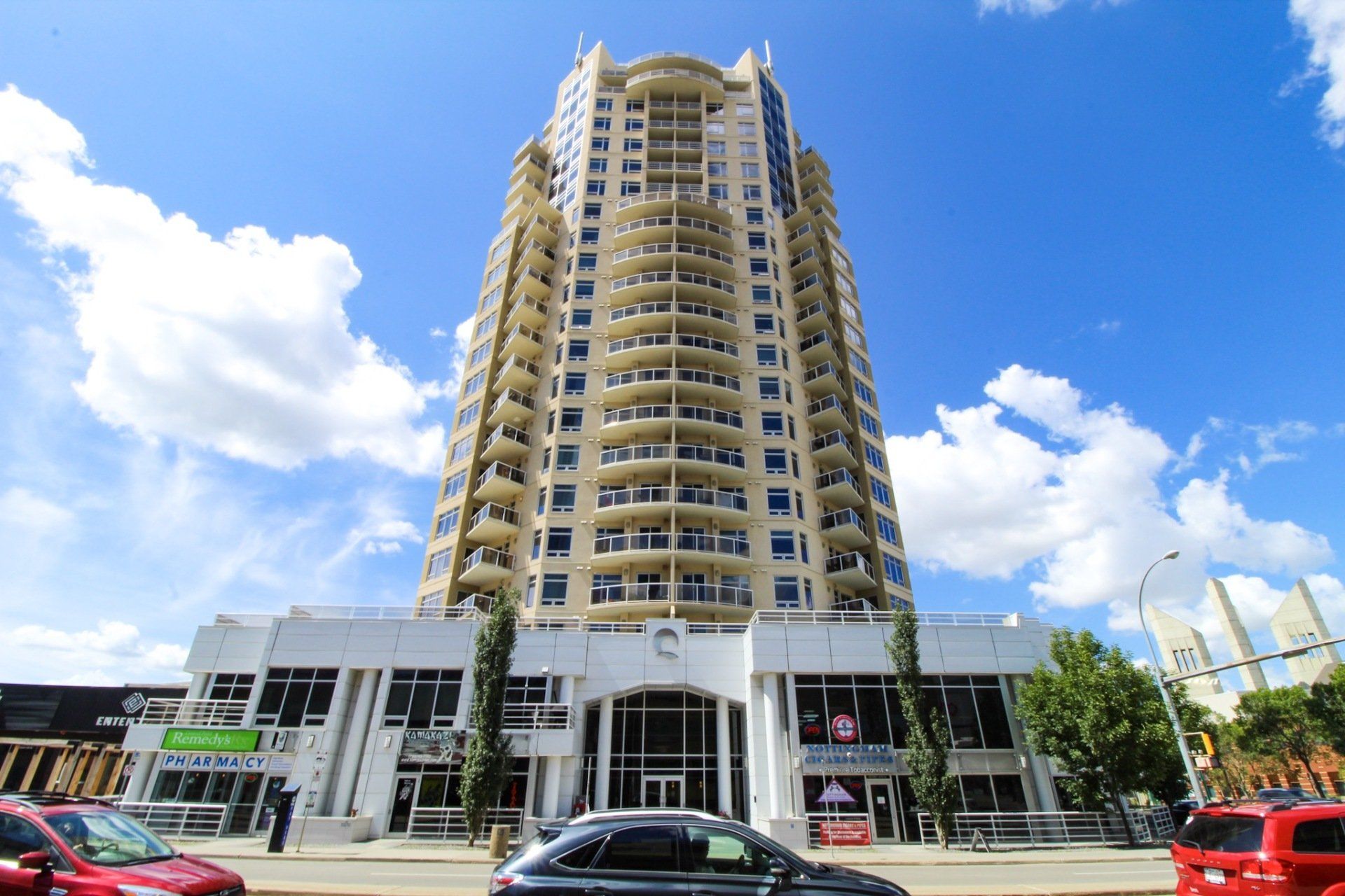 Cream coloured 20 story building with white steel podium in the daytime