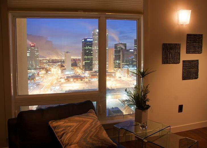 A cozy living room with a nighttime city view through large windows.