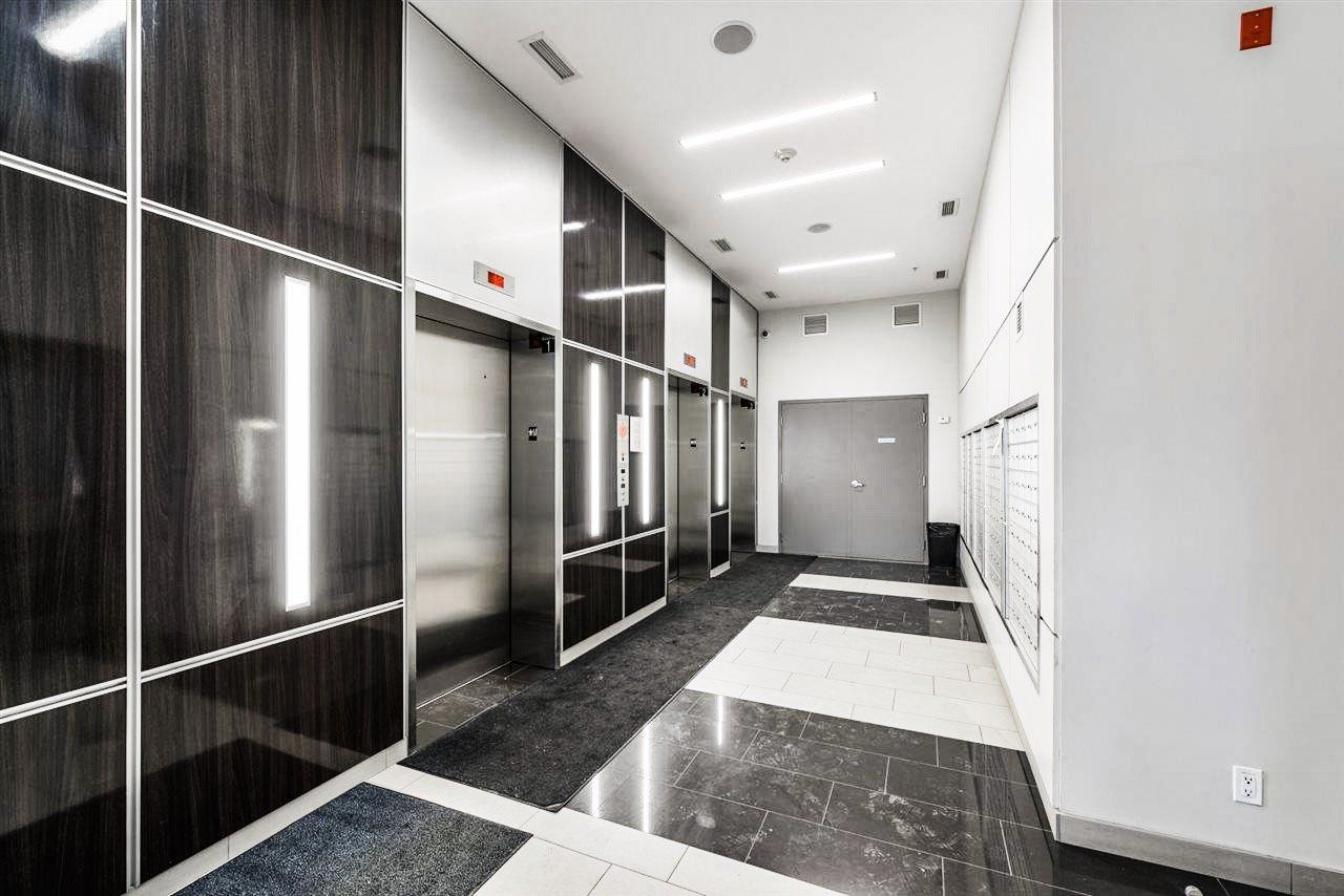 Elevator lobby with silver elevators, black and white marble floor, and mailboxes.