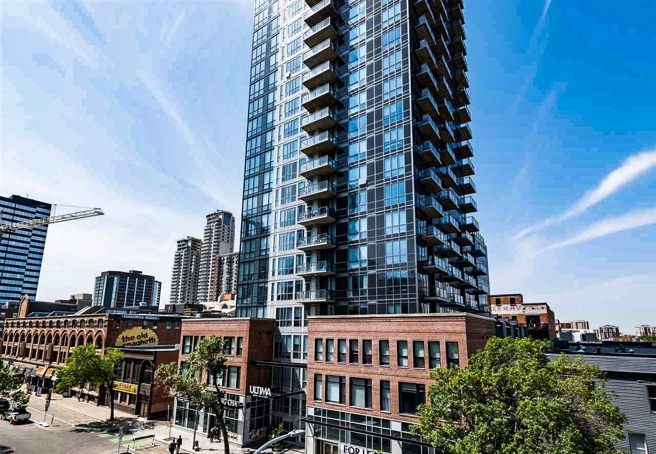 Blue steel and Glass tower with a red brick podium in the daytime