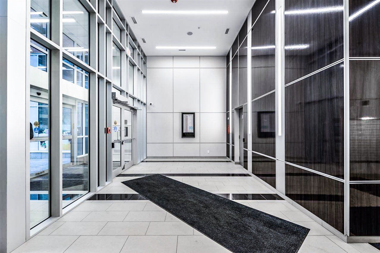 Hallway with glass walls, black rug, and white walls.