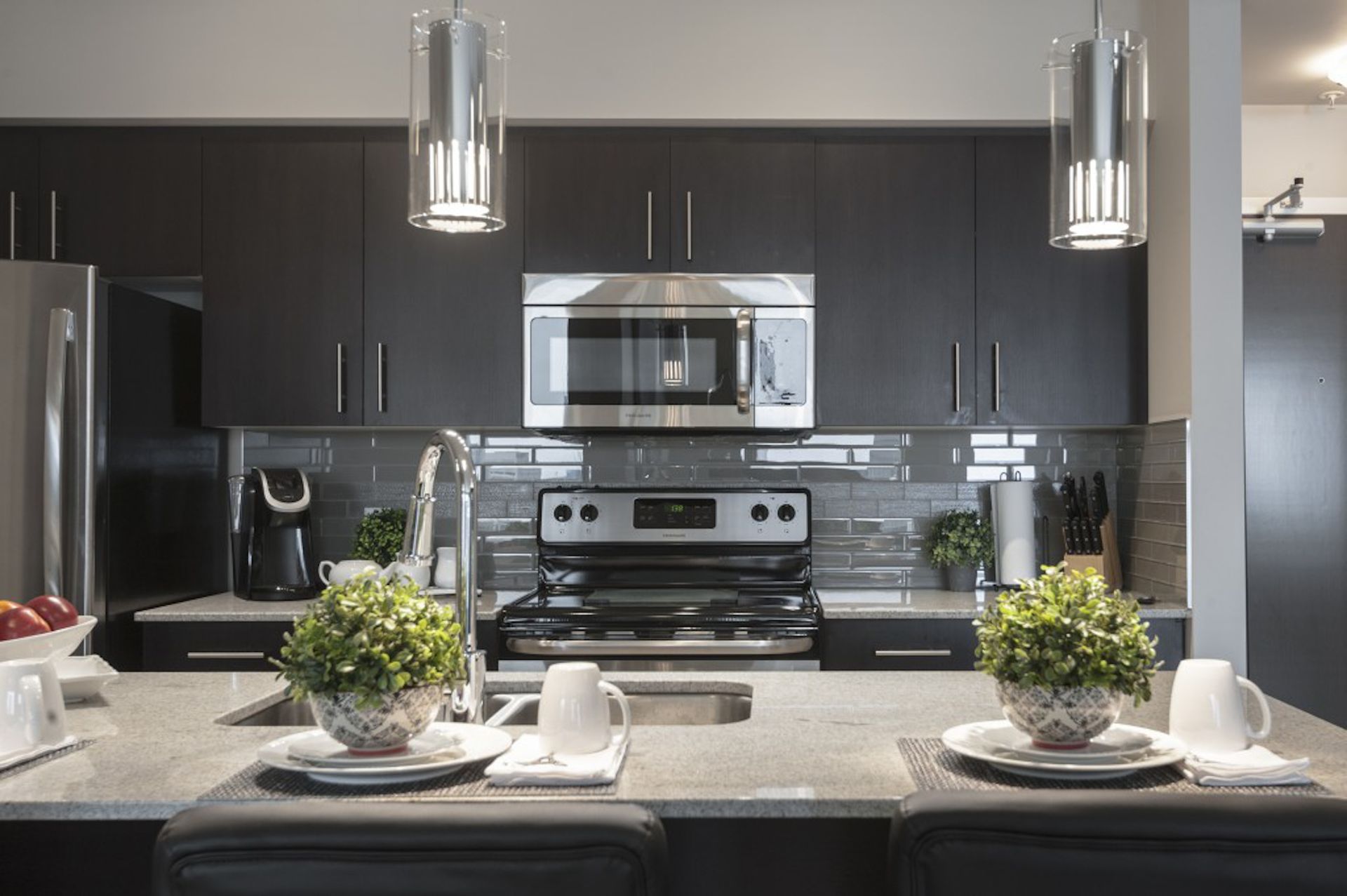 Modern kitchen with black cabinets, stainless steel appliances, and granite countertops.