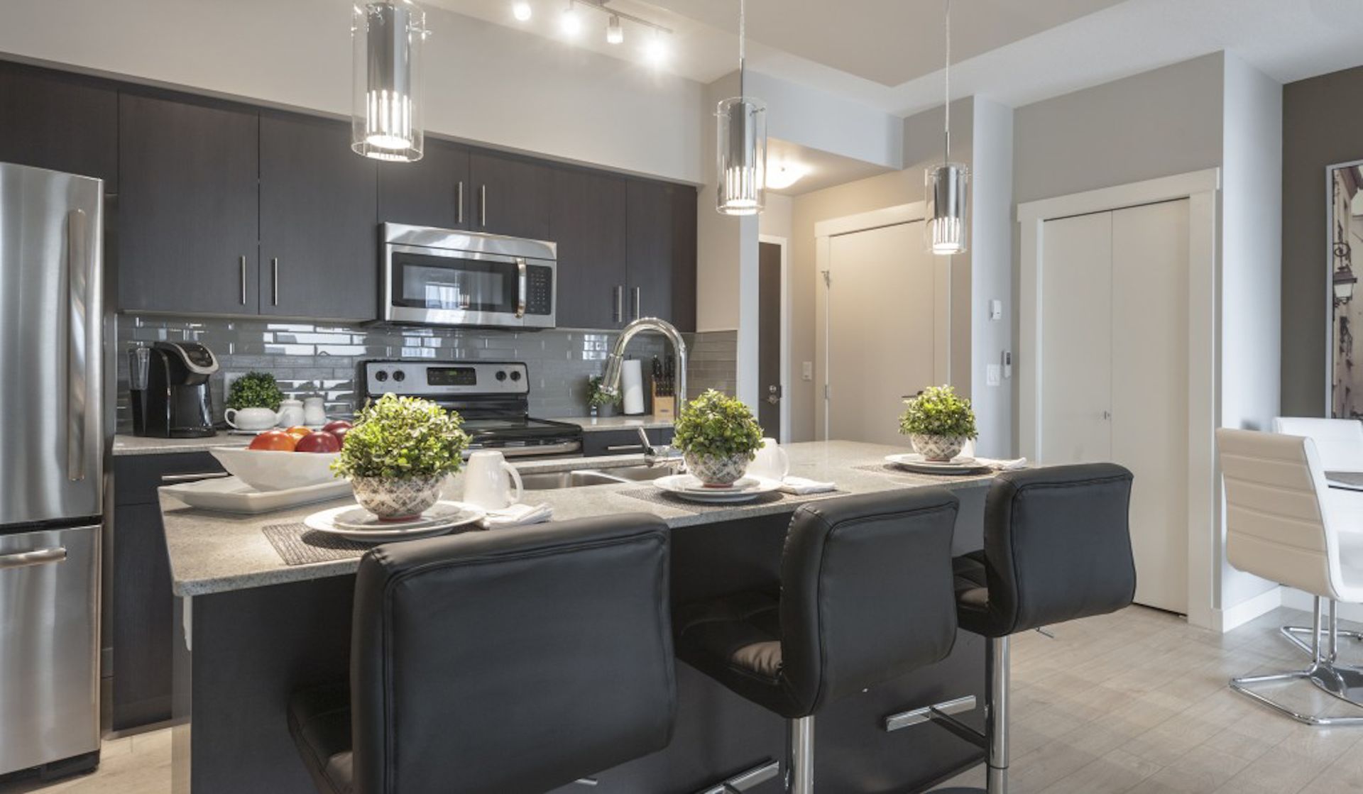 Modern kitchen with dark cabinets, stainless steel appliances, island with bar stools.