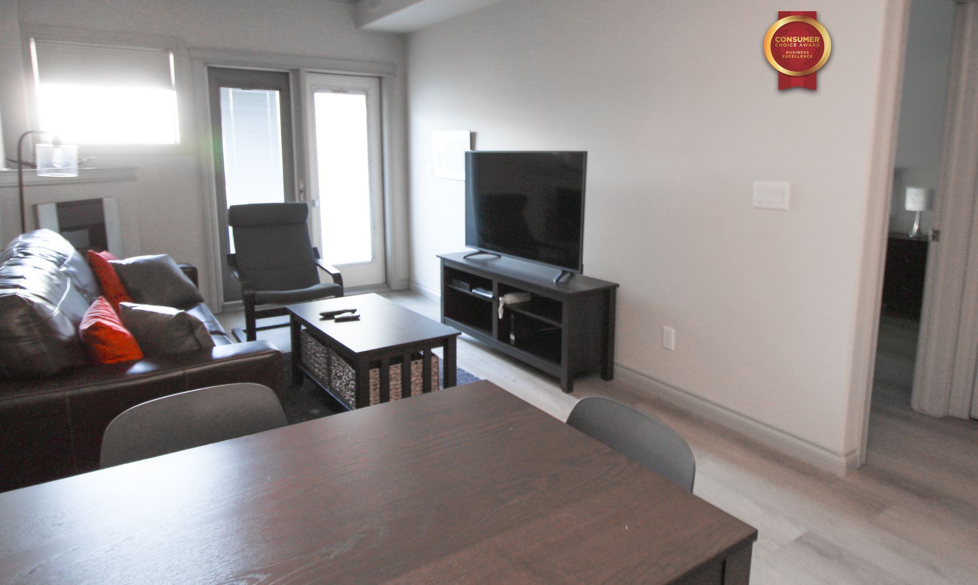 Living room with a sofa, TV, table, and chairs. Edmonton. Furnished suites