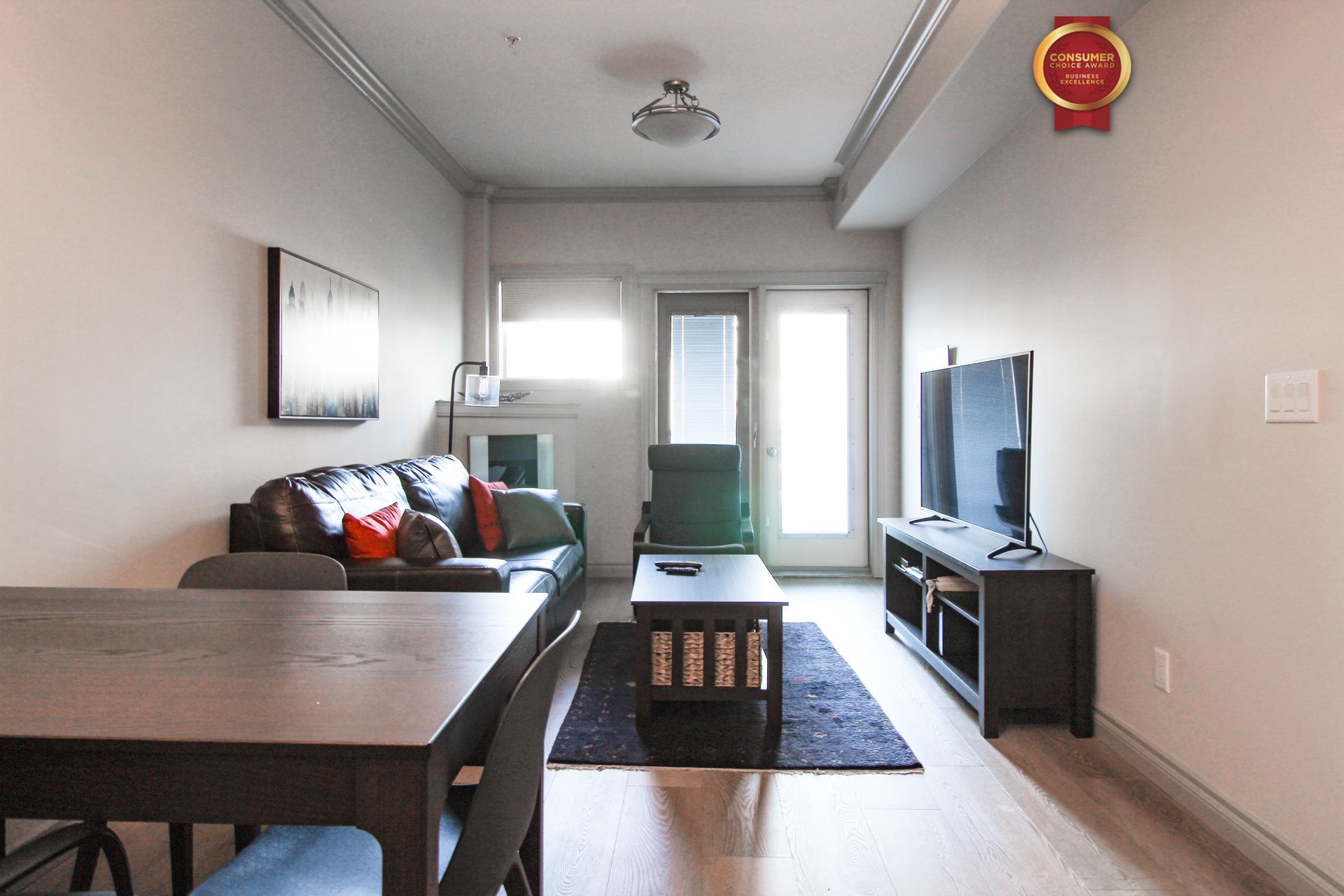 Living room with black sofa, TV, and wooden table.