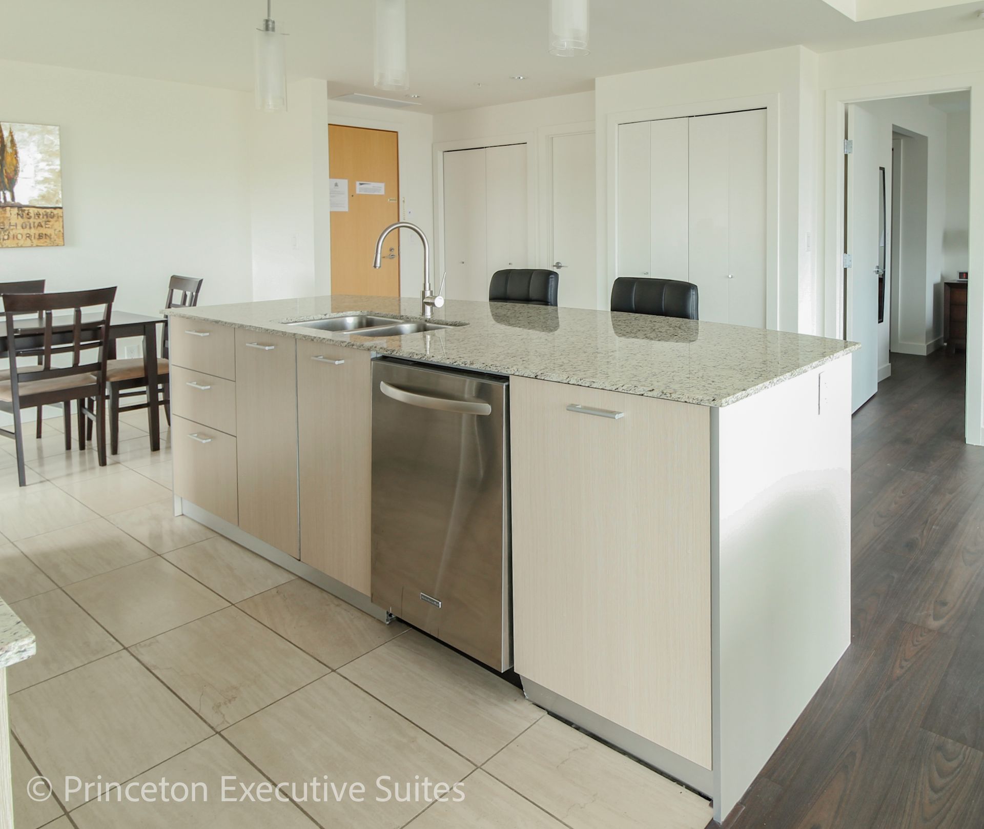 Modern kitchen with large island, stainless steel appliances, and light-colored cabinetry.