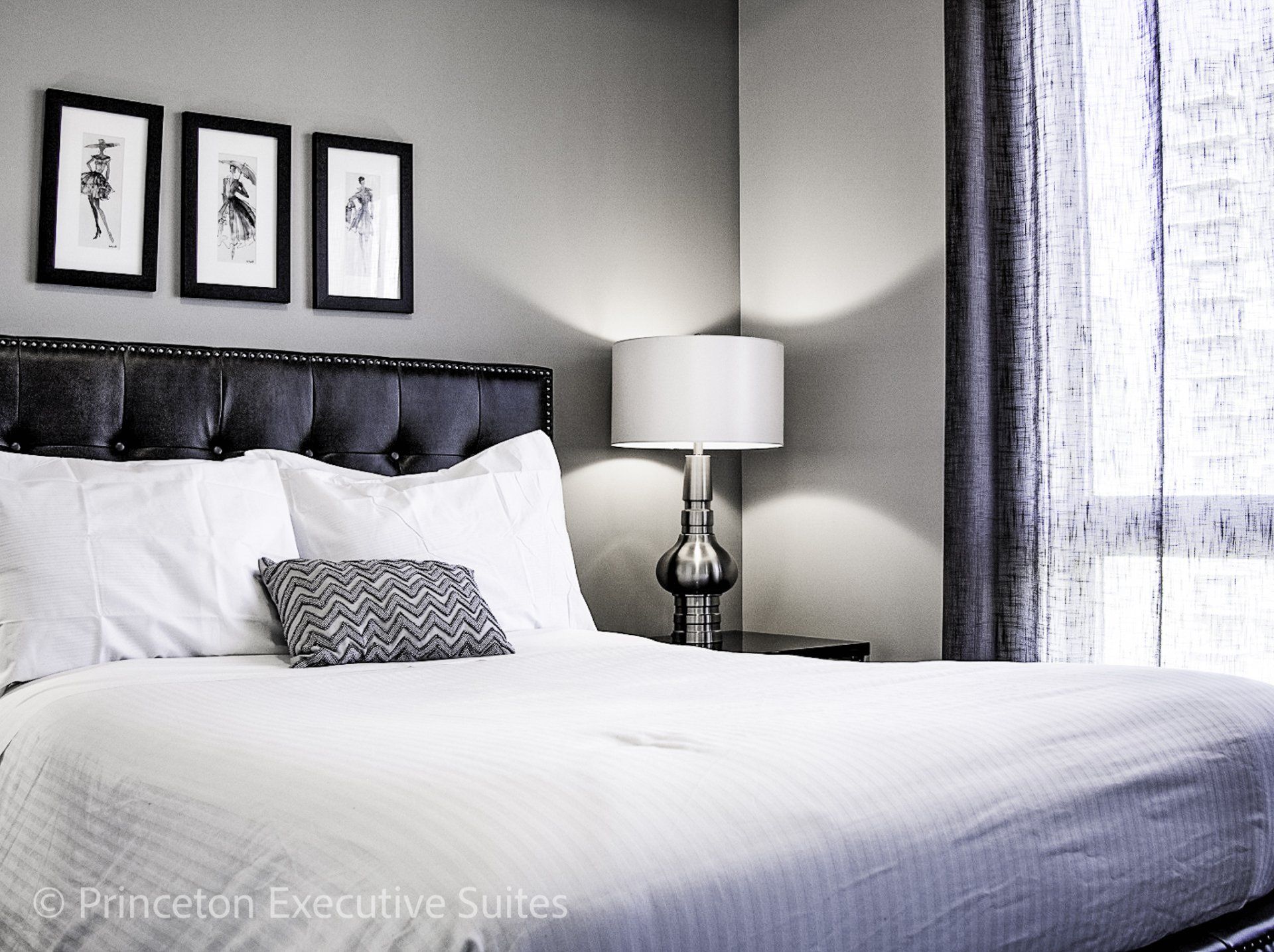 Master bedroom grey headboard, silver lamp 3 pictures on the wall above headboard Edmonton furnished apartments