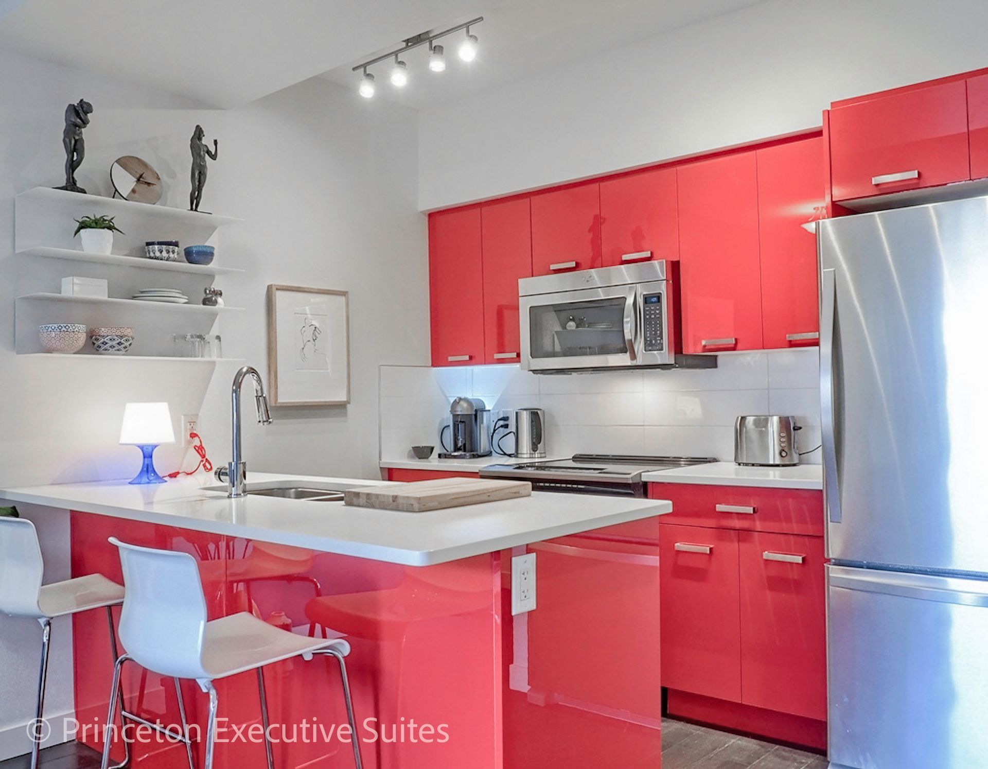 Modern kitchen with red cabinets, stainless steel appliances, and a white island.