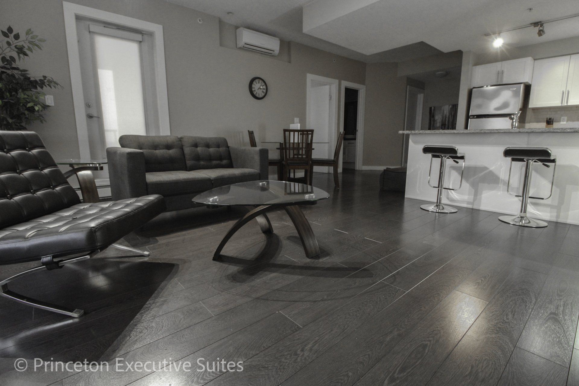 dark hardwood flooring grey couch and black Barcelona chair edmonton extended stay suites