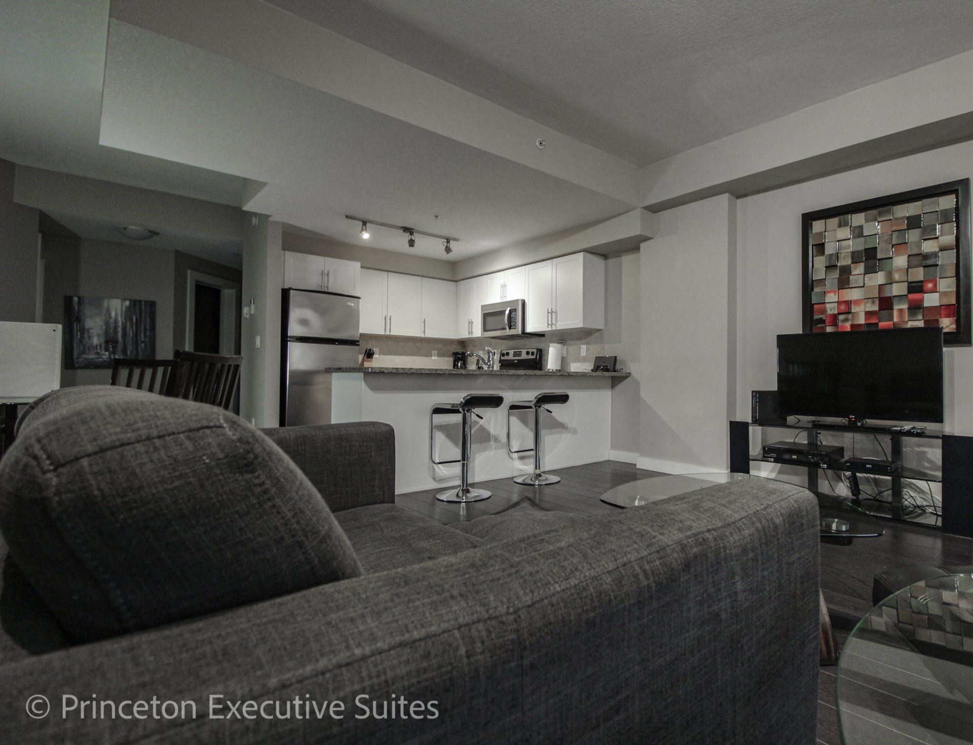 White kitchen with granite counter tops grey couch silver and black barstools edmonton furnished suites