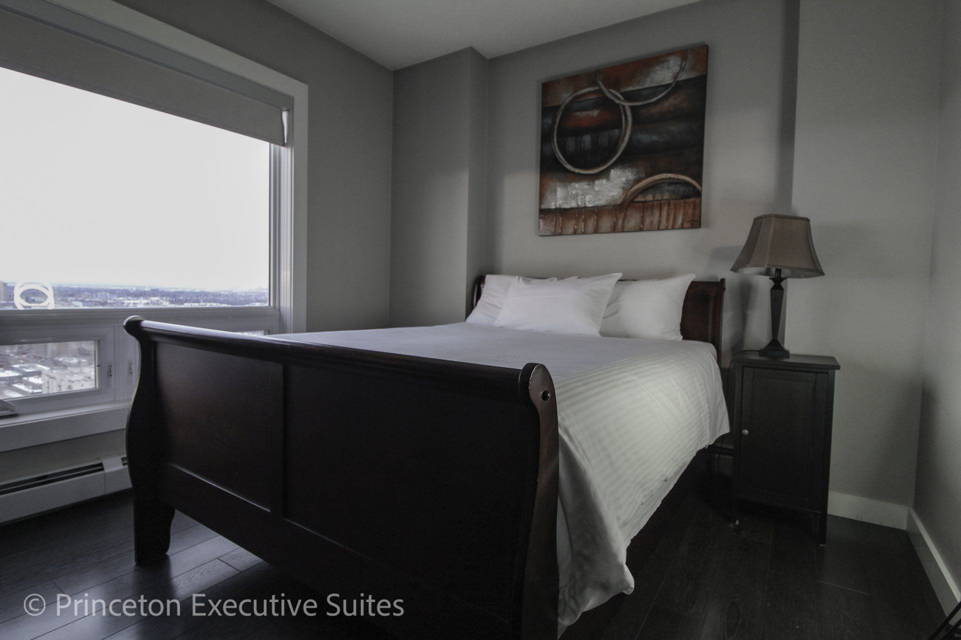 Red slay bed with picture above the headboard and white linens on the bed