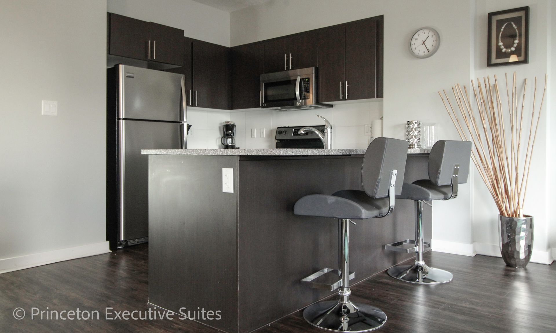 Modern kitchen with a bar, stainless steel appliances, and two stools.