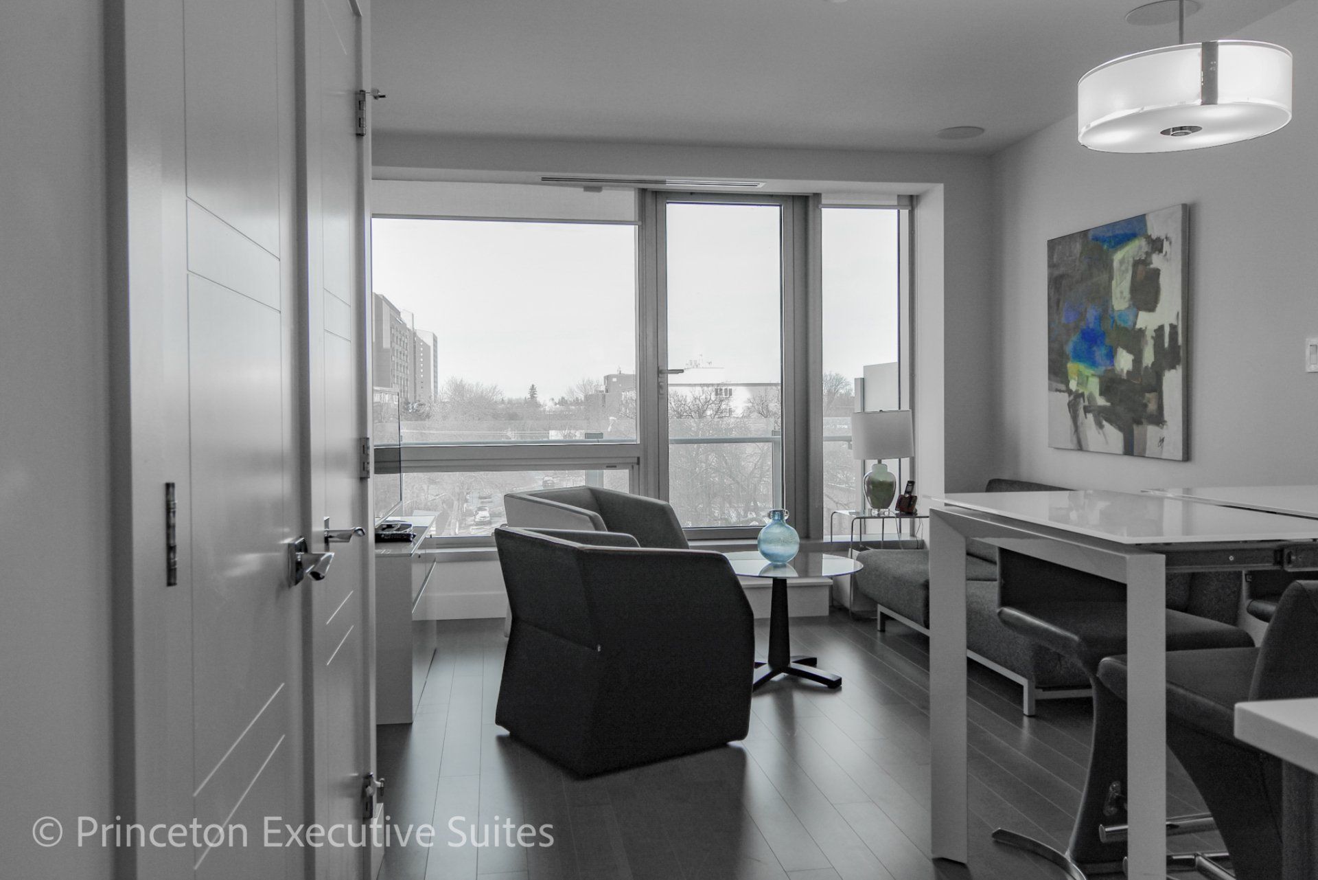 Living area with white kitchen table and grey and black living furniture in the back ground of this Edmonton executive suite
