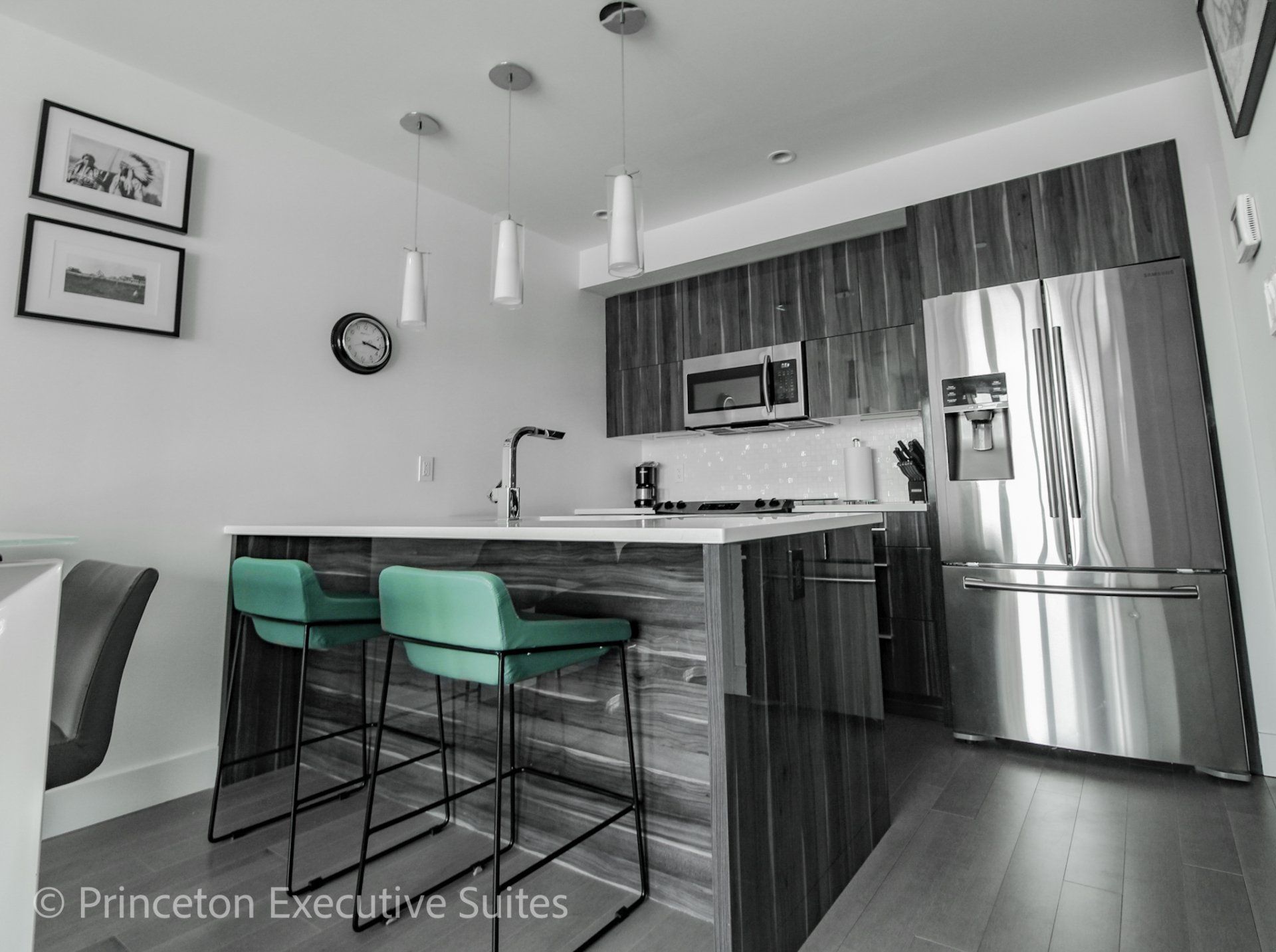 Turquoise barstools in front of a eating bar with white counter tops and stainless steel kitchen in the back ground