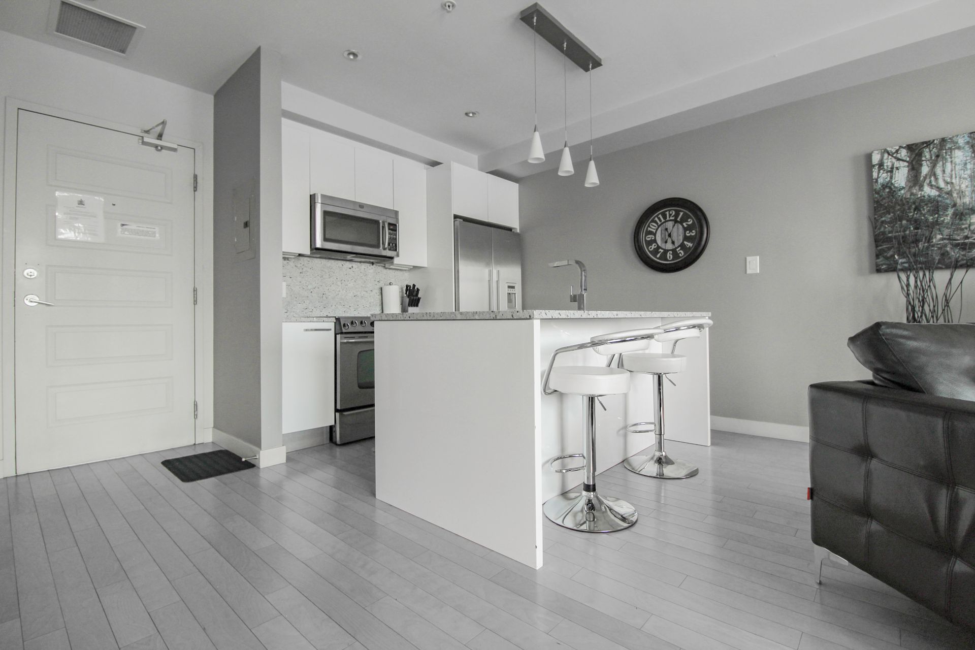 Modern kitchen with white cabinets, island, stainless steel appliances, and bar stools.