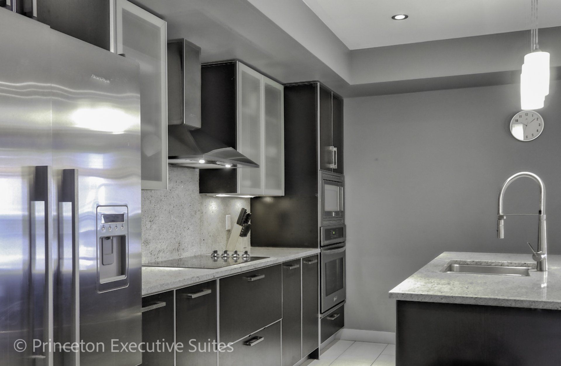 Modern kitchen with stainless steel appliances, dark cabinets, granite countertops.