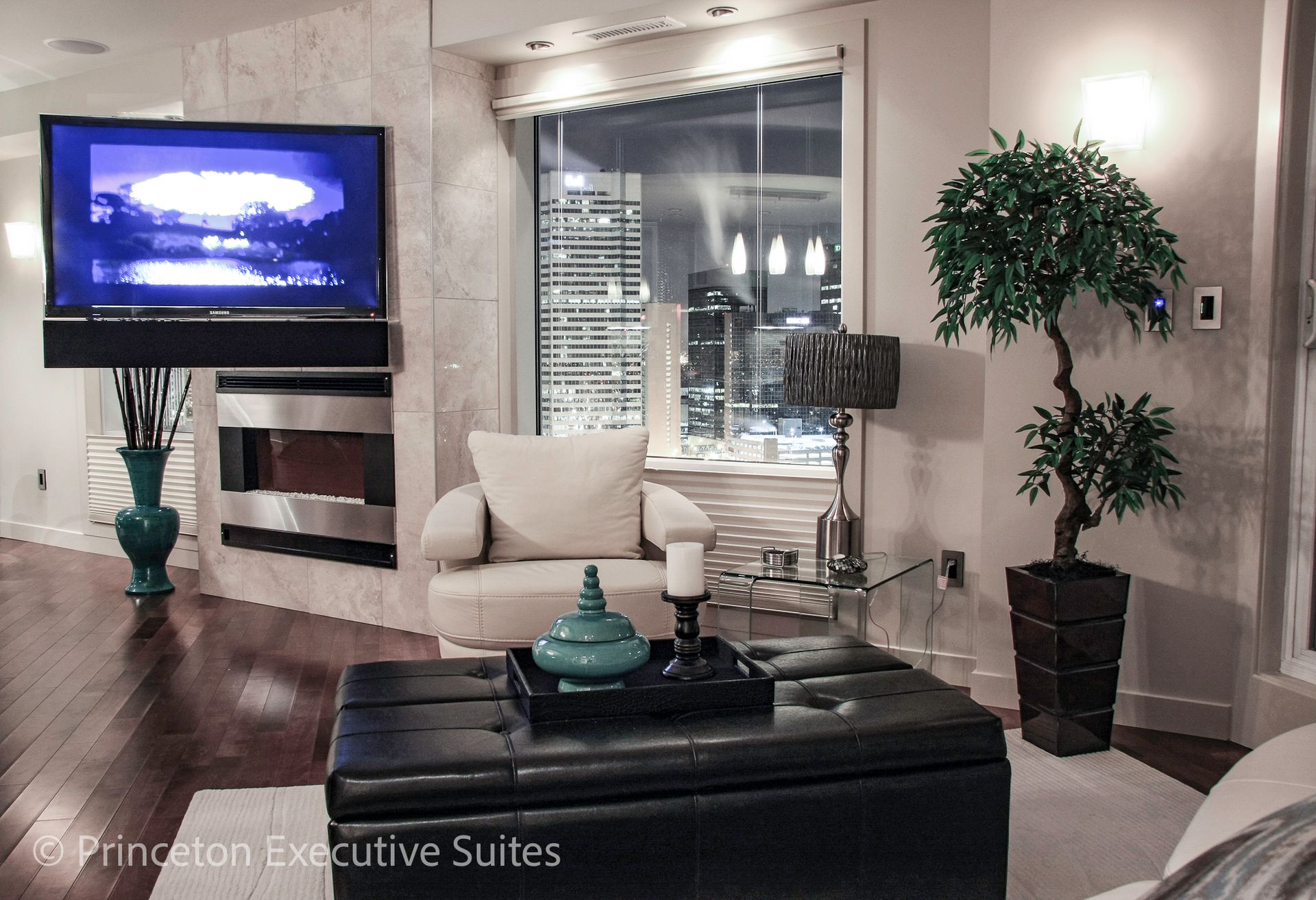 Cozy living room with TV, fireplace, armchair, and city view at night.