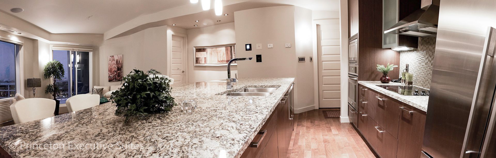 Modern kitchen with granite countertops, stainless steel appliances, and wood flooring.
