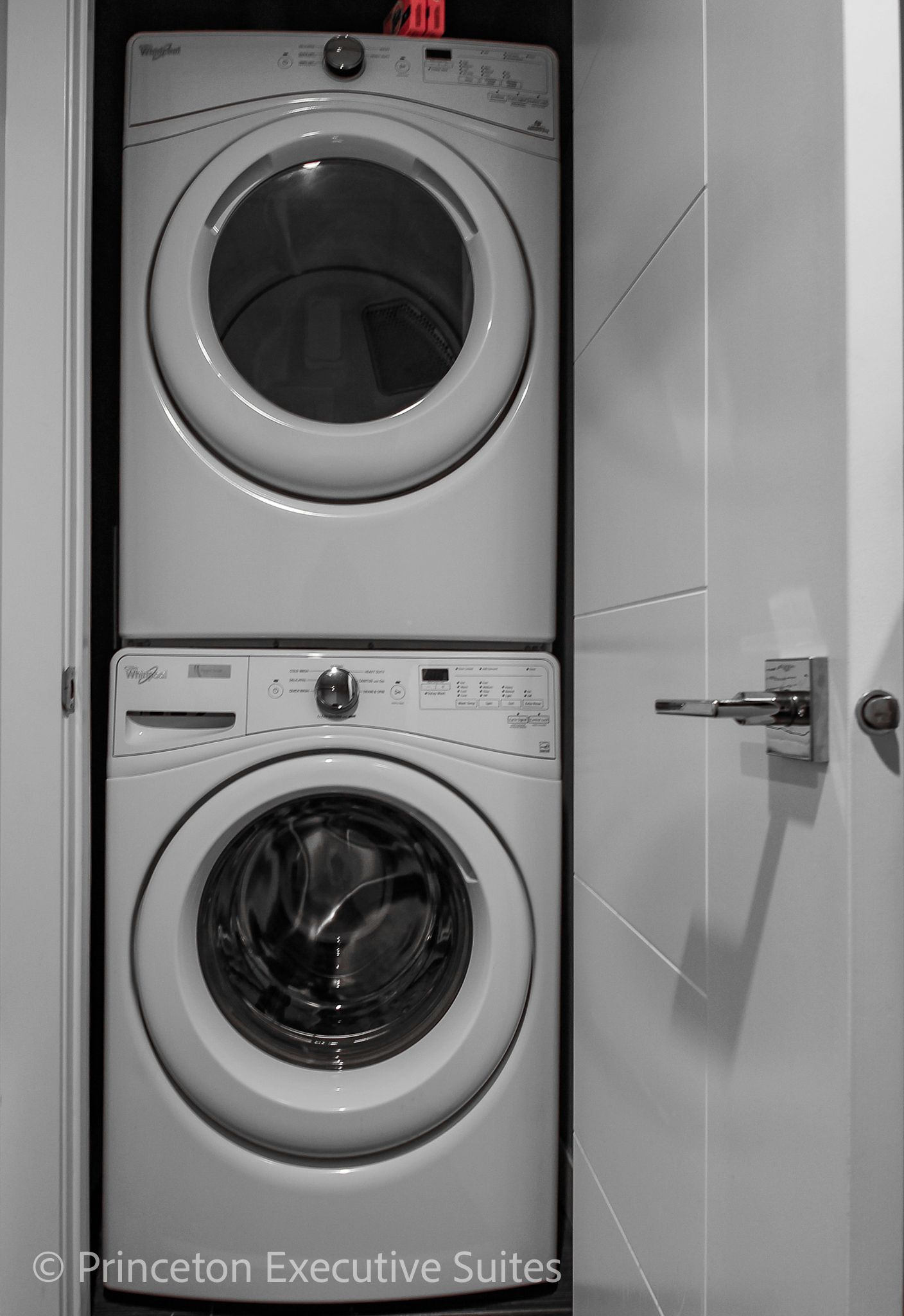 Stacked white Whirlpool washer and dryer in a closet. Door partially open, handle visible.