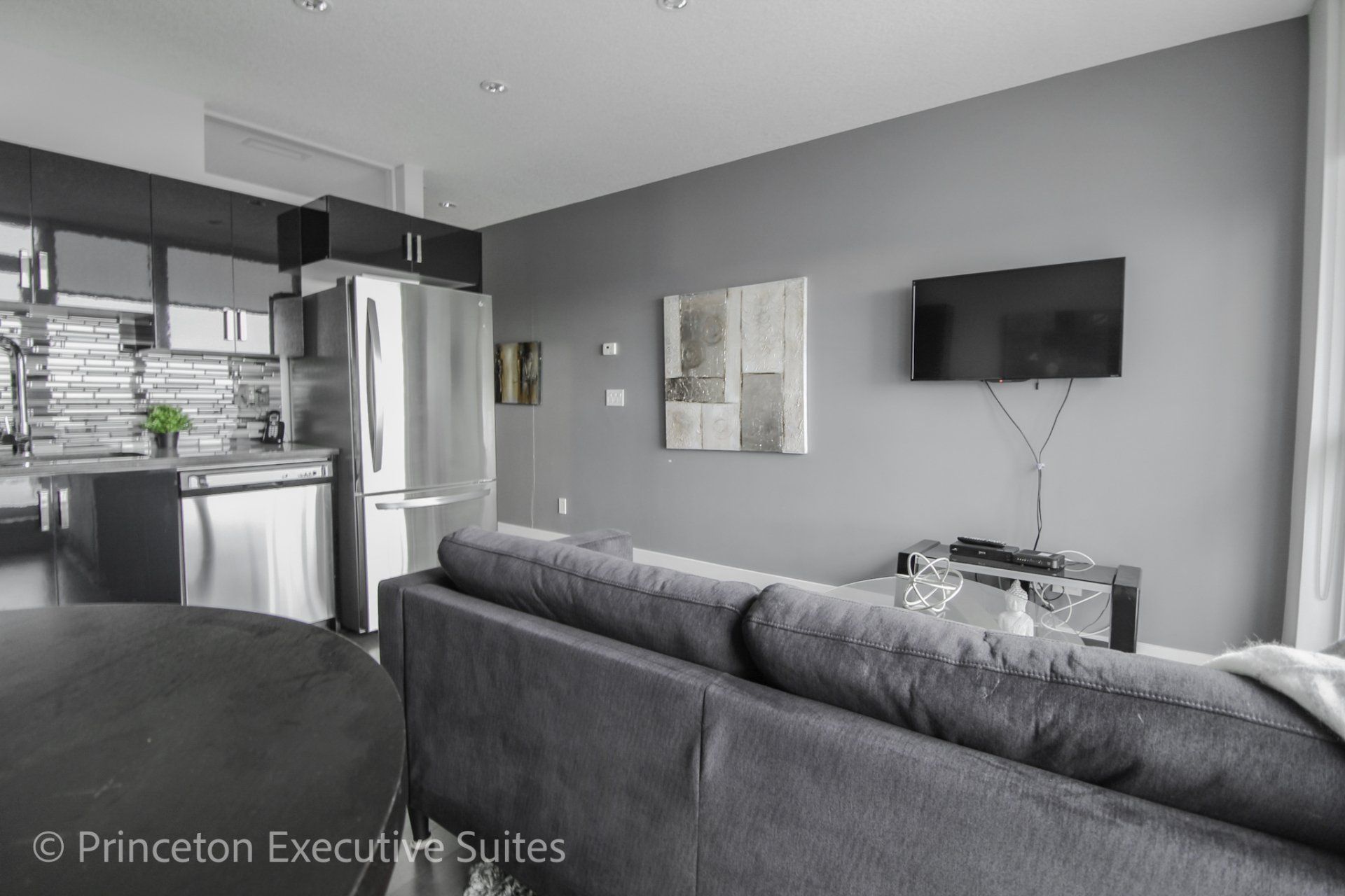 Living room of a Ultima furnished suite with TV and brown couch