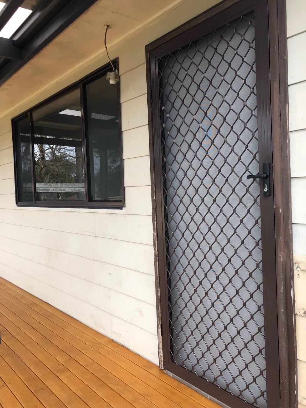 A Door With A Diamond Pattern On It Is Sitting On A Wooden Deck — Central Coast Flyscreen Service In West Gosford, NSW