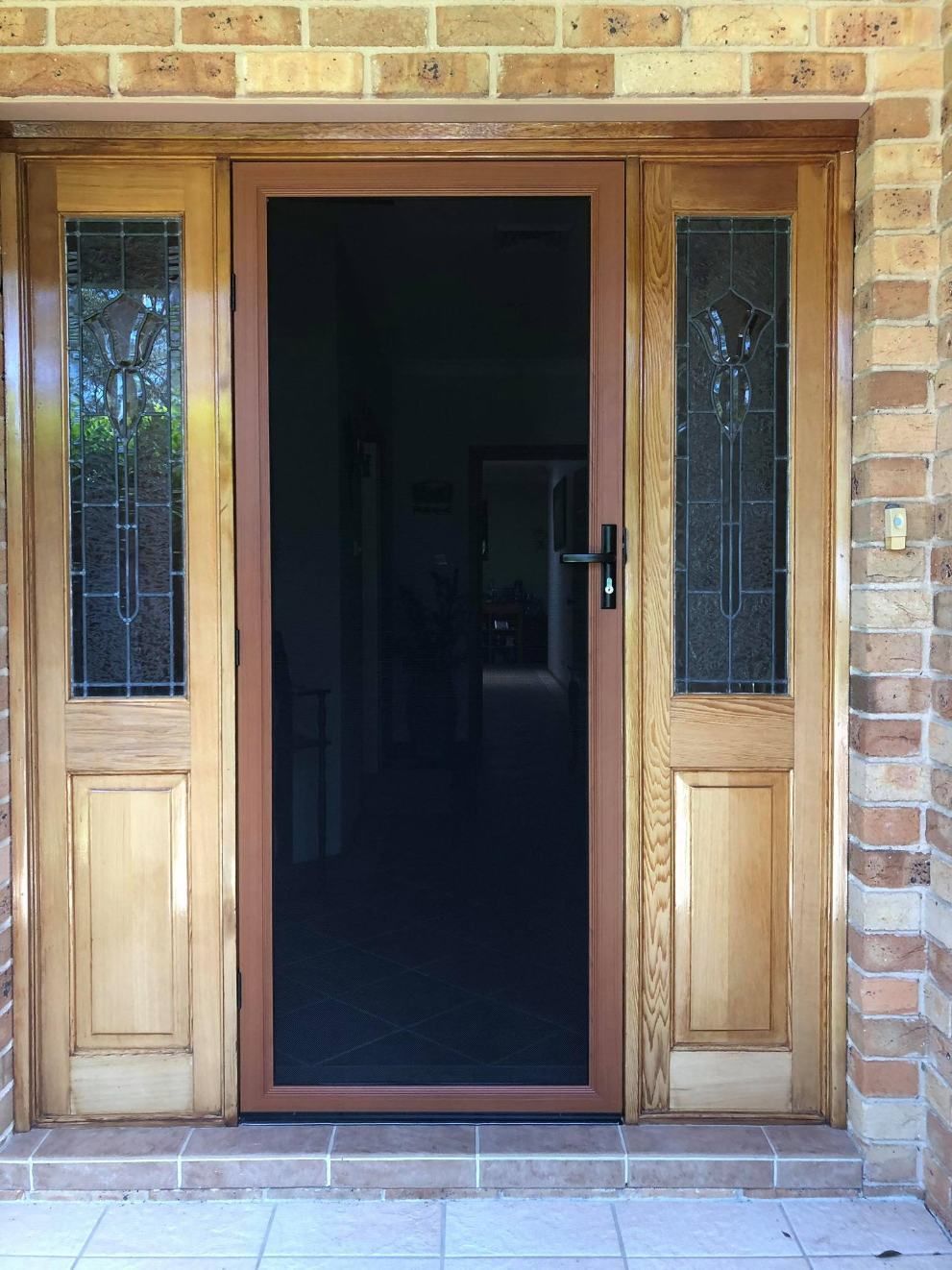 A Wooden Door With A Screen On It Is In Front Of A Brick Wall — Central Coast Flyscreen Service In Warnervale, NSW