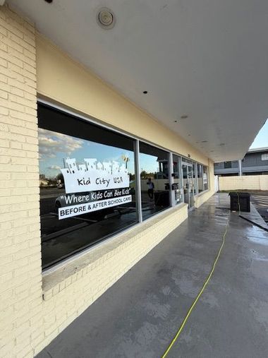 Glass storefront with gold text, modern staircase visible, and a gravel bed at the bottom.