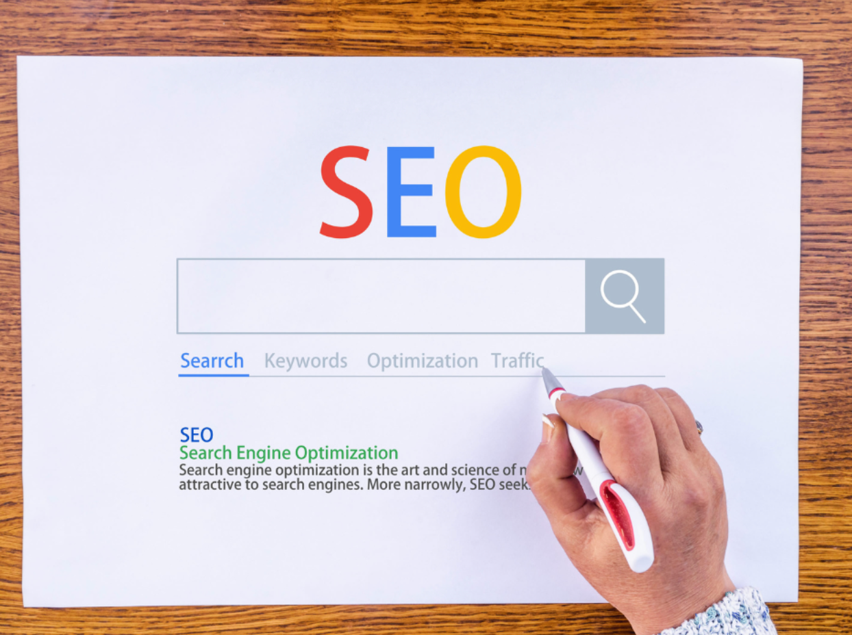 A person is writing on a piece of paper that says seo