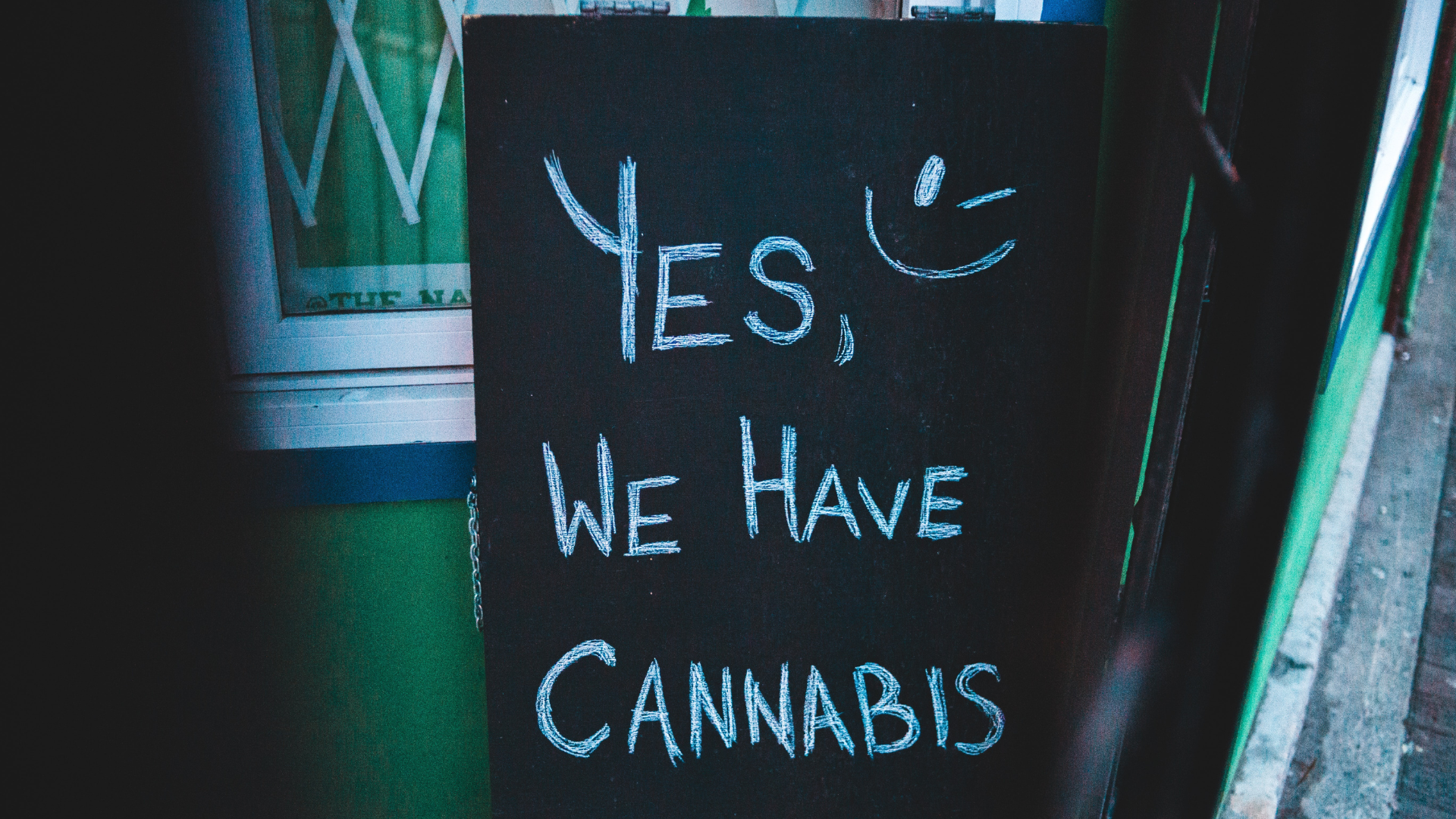 Chalkboard sign outside a shop with the handwritten message 'Yes, we have cannabis