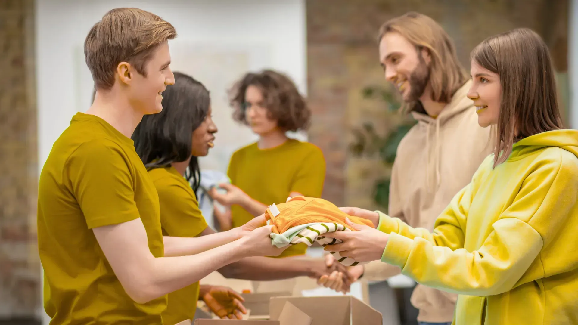 A group of people are giving clothes to each other in a room.