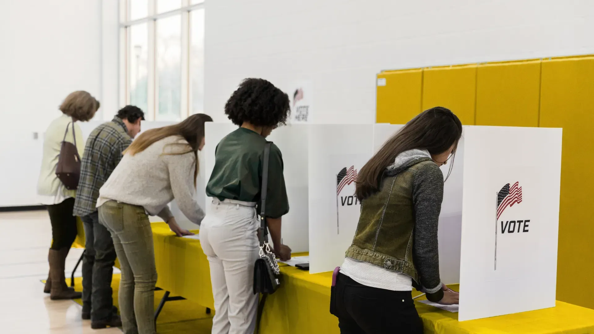 A group of people are standing around a table at a voting booth.