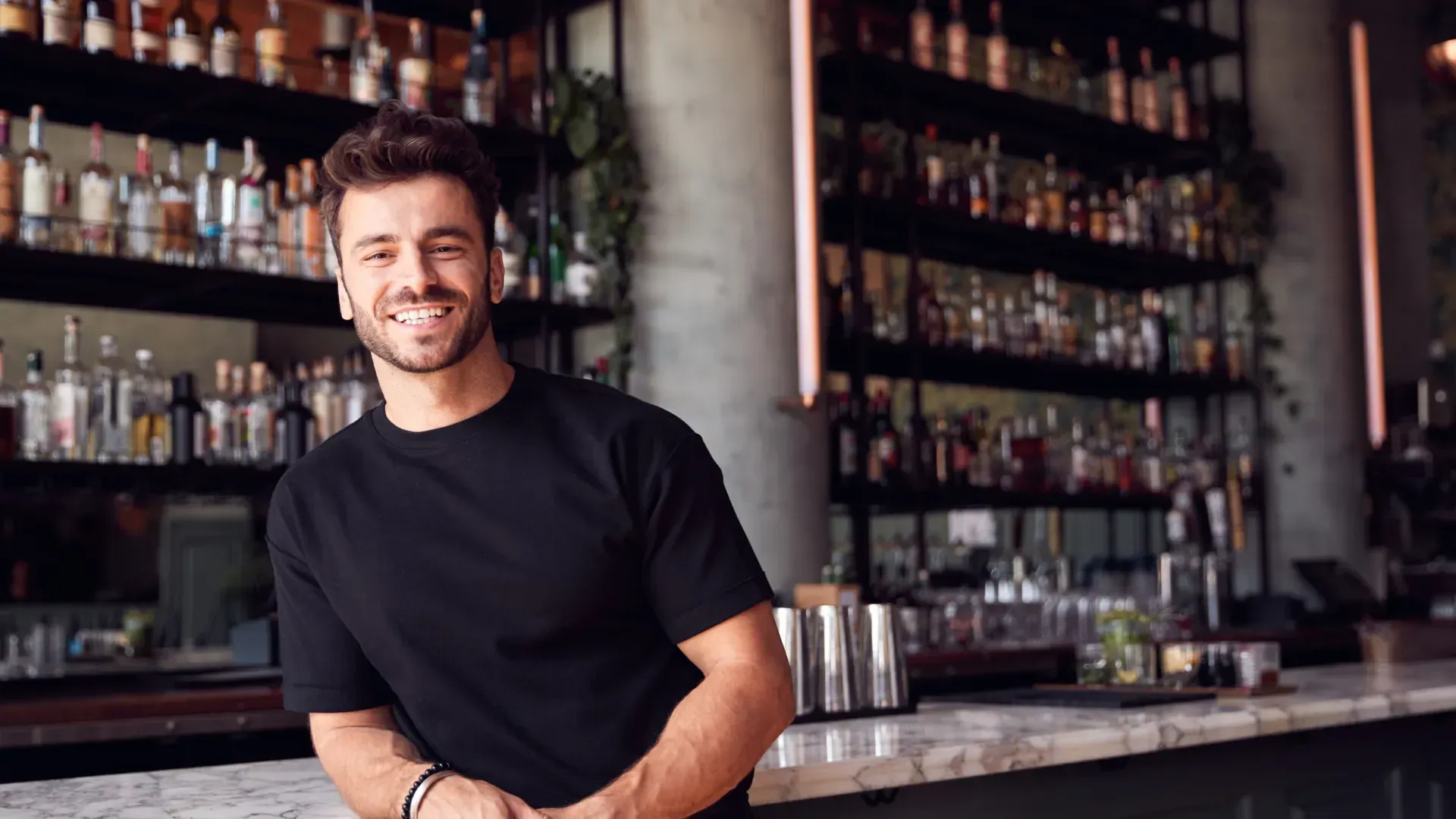 A man is standing behind a bar in a restaurant.
