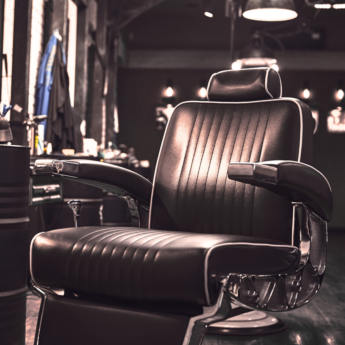 A barber chair is sitting in a dark room in a barber shop.