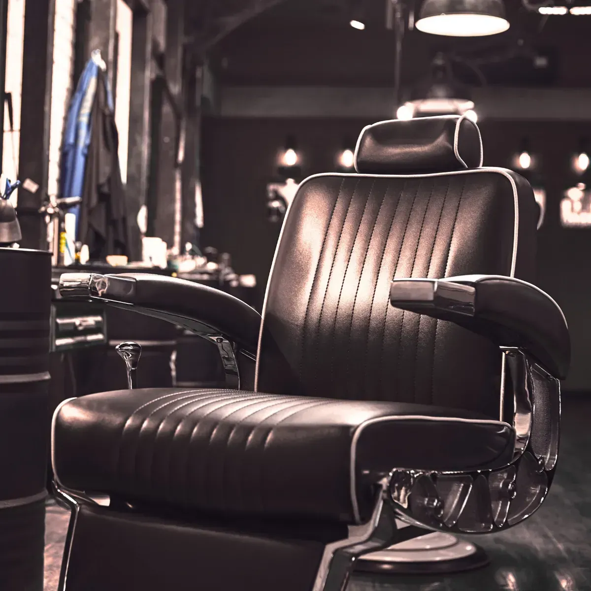 A barber chair is sitting in a dark room in a barber shop.