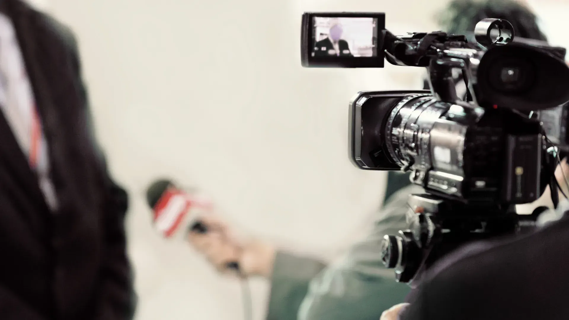 A man in a suit is being interviewed by a cameraman while holding a microphone.