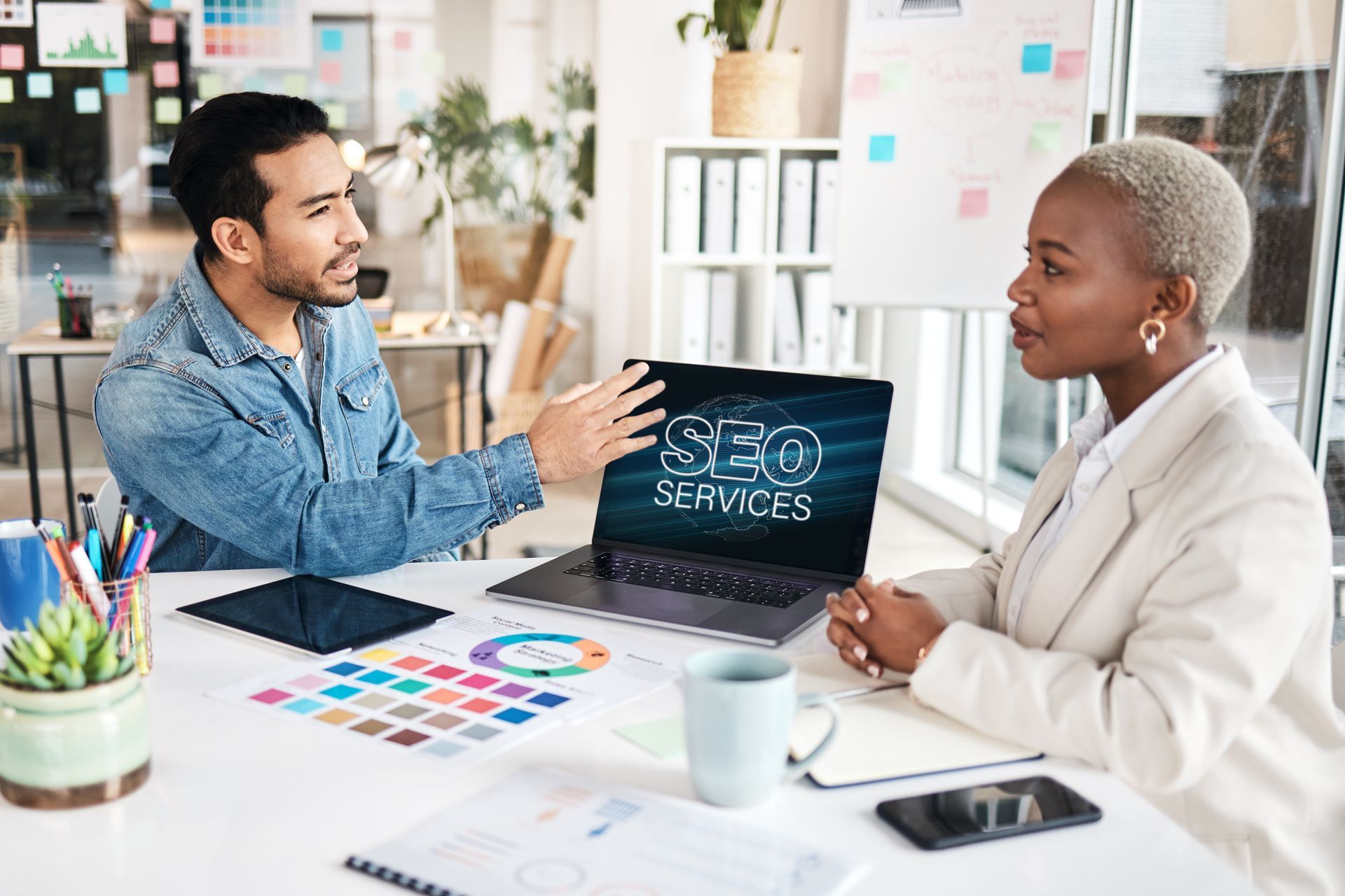 A man and a woman are sitting at a table with a laptop.