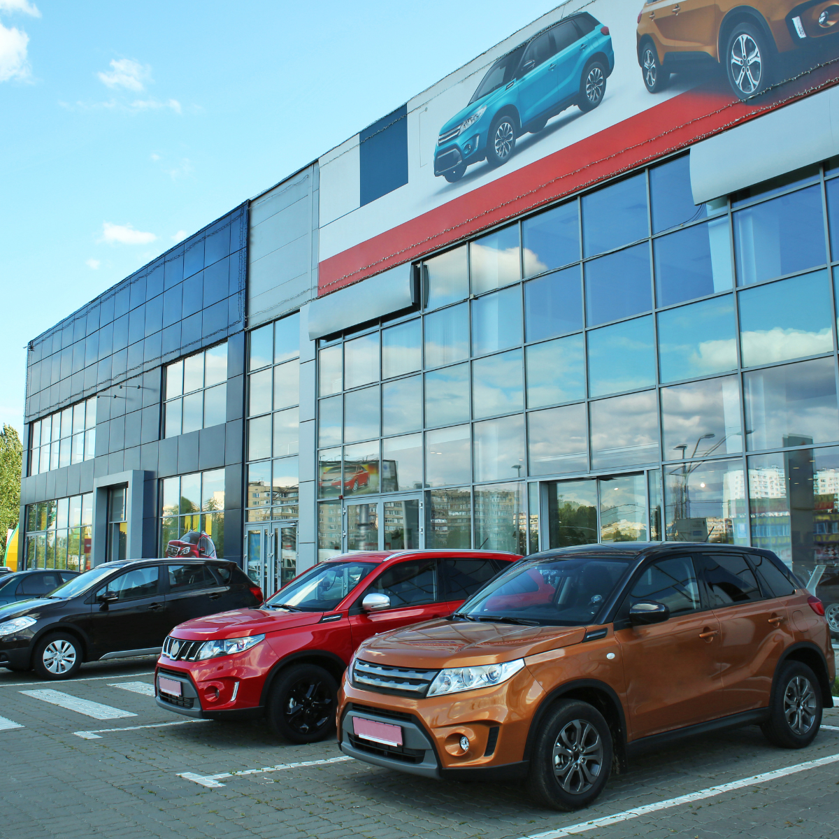 A row of cars are parked in front of a car dealership