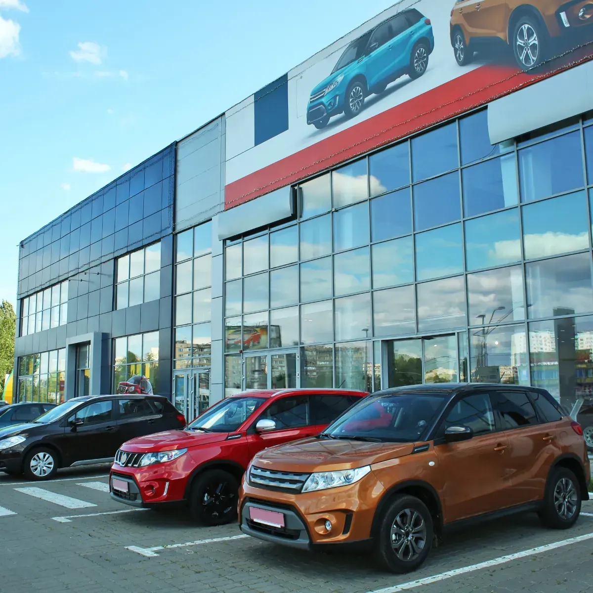 A row of cars are parked in front of a car dealership