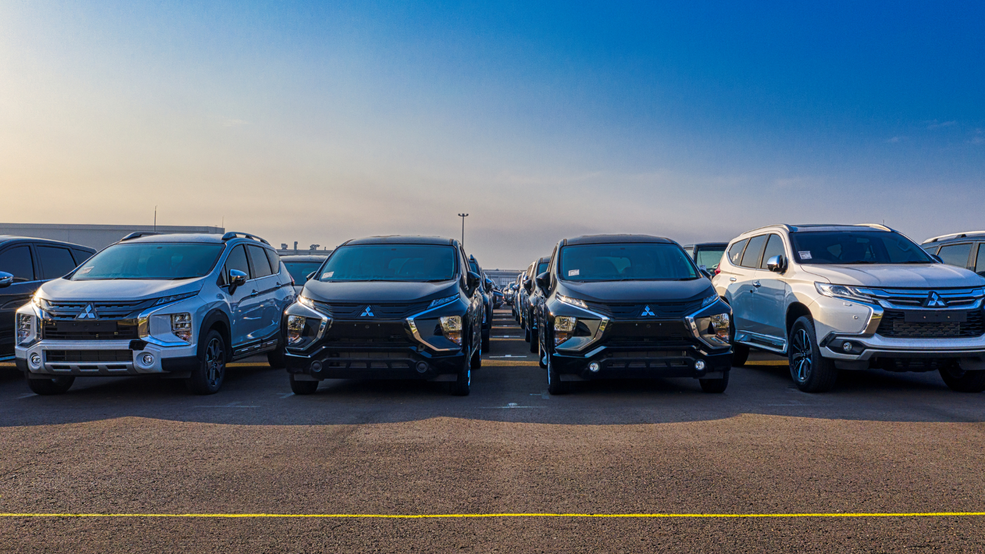 A row of cars are parked in a parking lot.