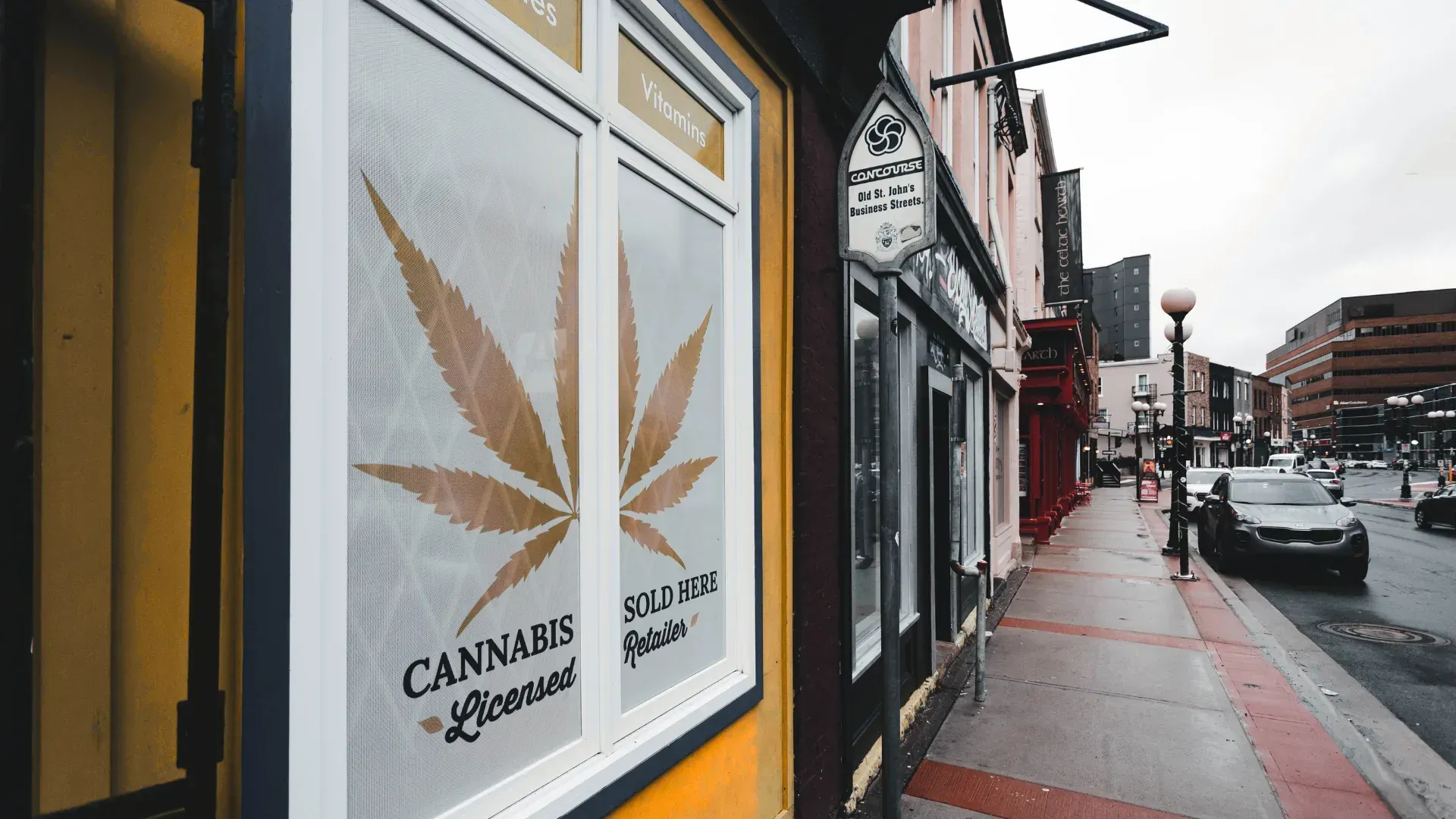 Street view of a cannabis store with a large cannabis leaf poster on the window