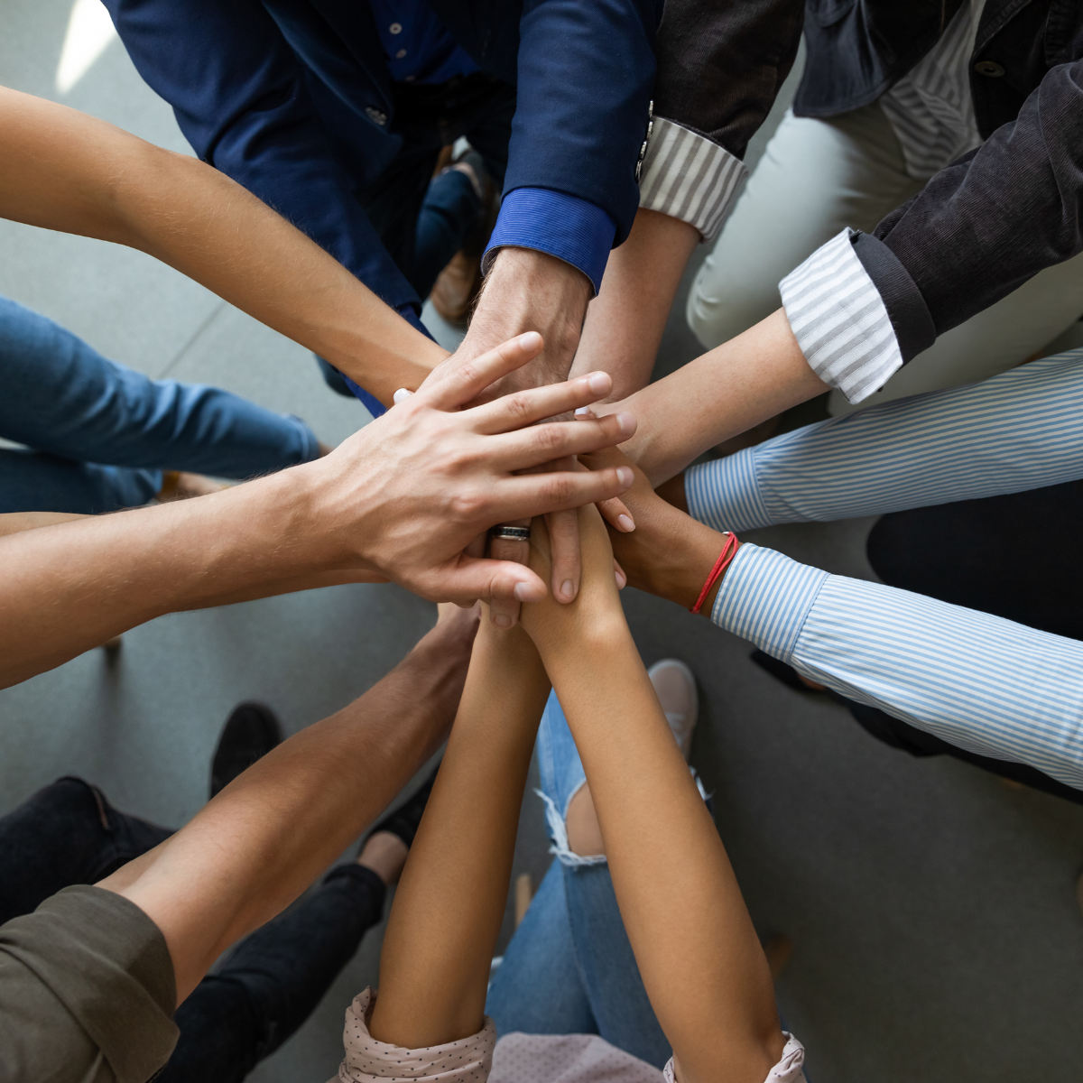 A group of people putting their hands together in a circle