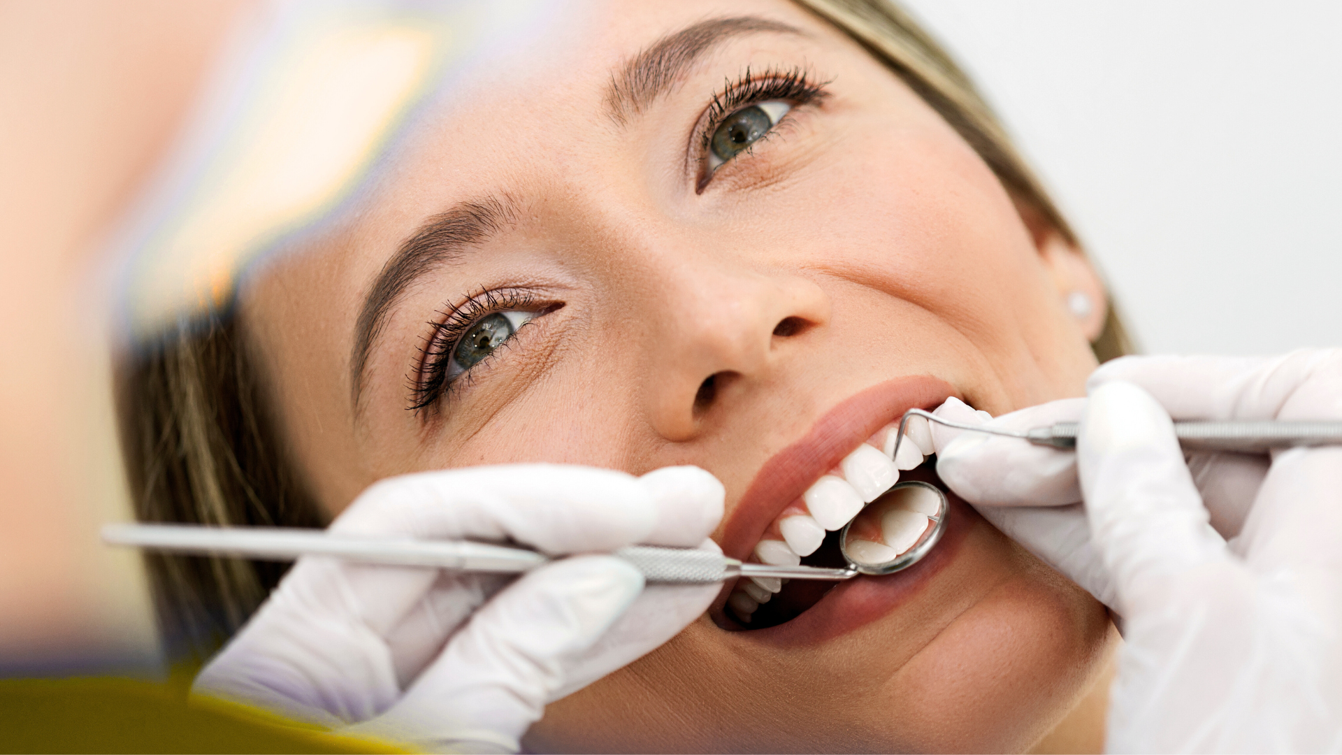 A woman is getting her teeth examined by a dentist.