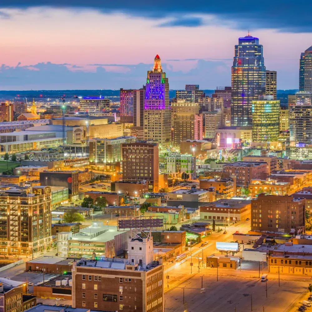 An aerial view of a city at night with a purple building in the foreground.