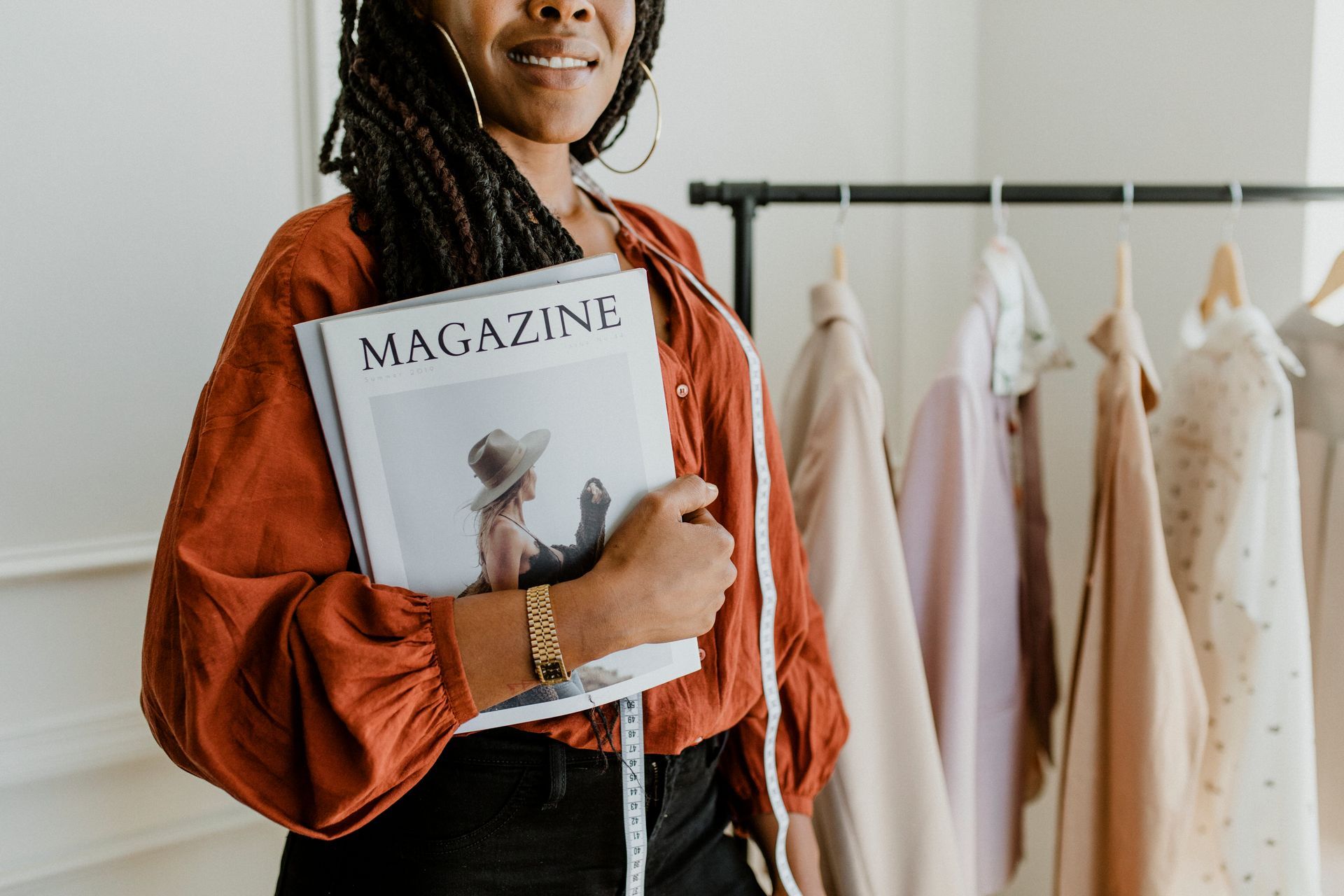 A woman is holding a magazine and a measuring tape.
