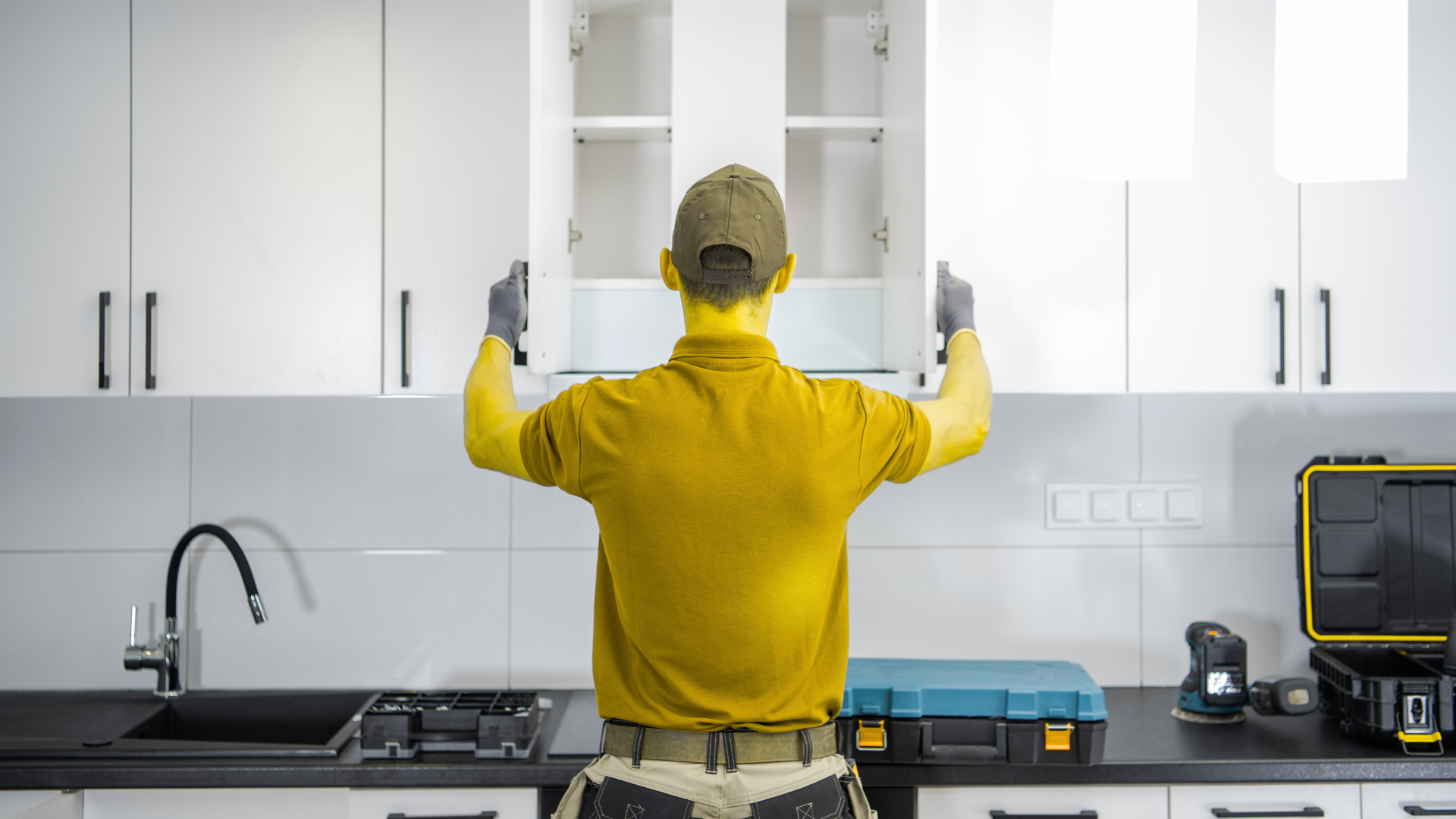 A man is installing cabinets in a kitchen.