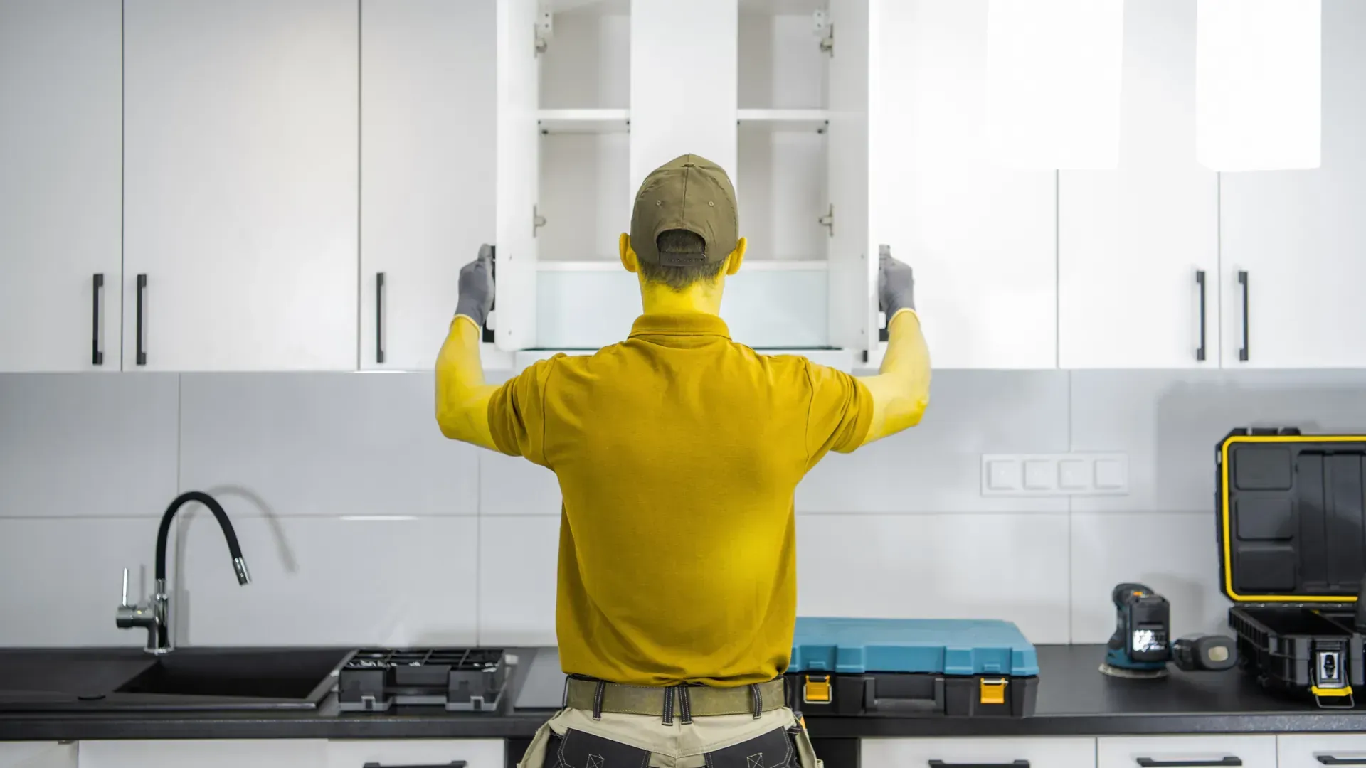 A man is installing cabinets in a kitchen.